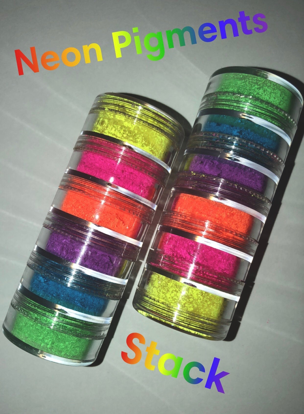 A vibrant stack of six neon pigments in assorted colors including yellow, green, pink, purple, orange, and blue, perfect for bold makeup looks.