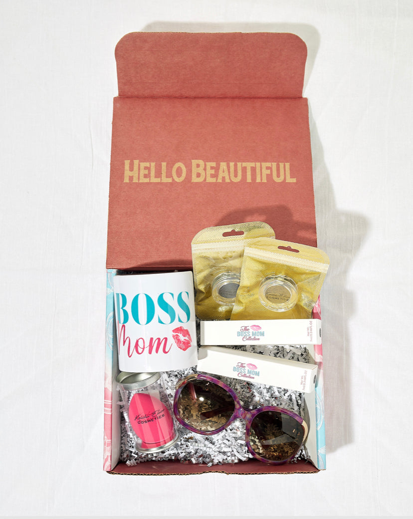 The Boss Mom Beauty Box featuring cosmetics and accessories for mothers, including a mug, sunglasses, makeup sponge, lip glosses, and eyeshadows.