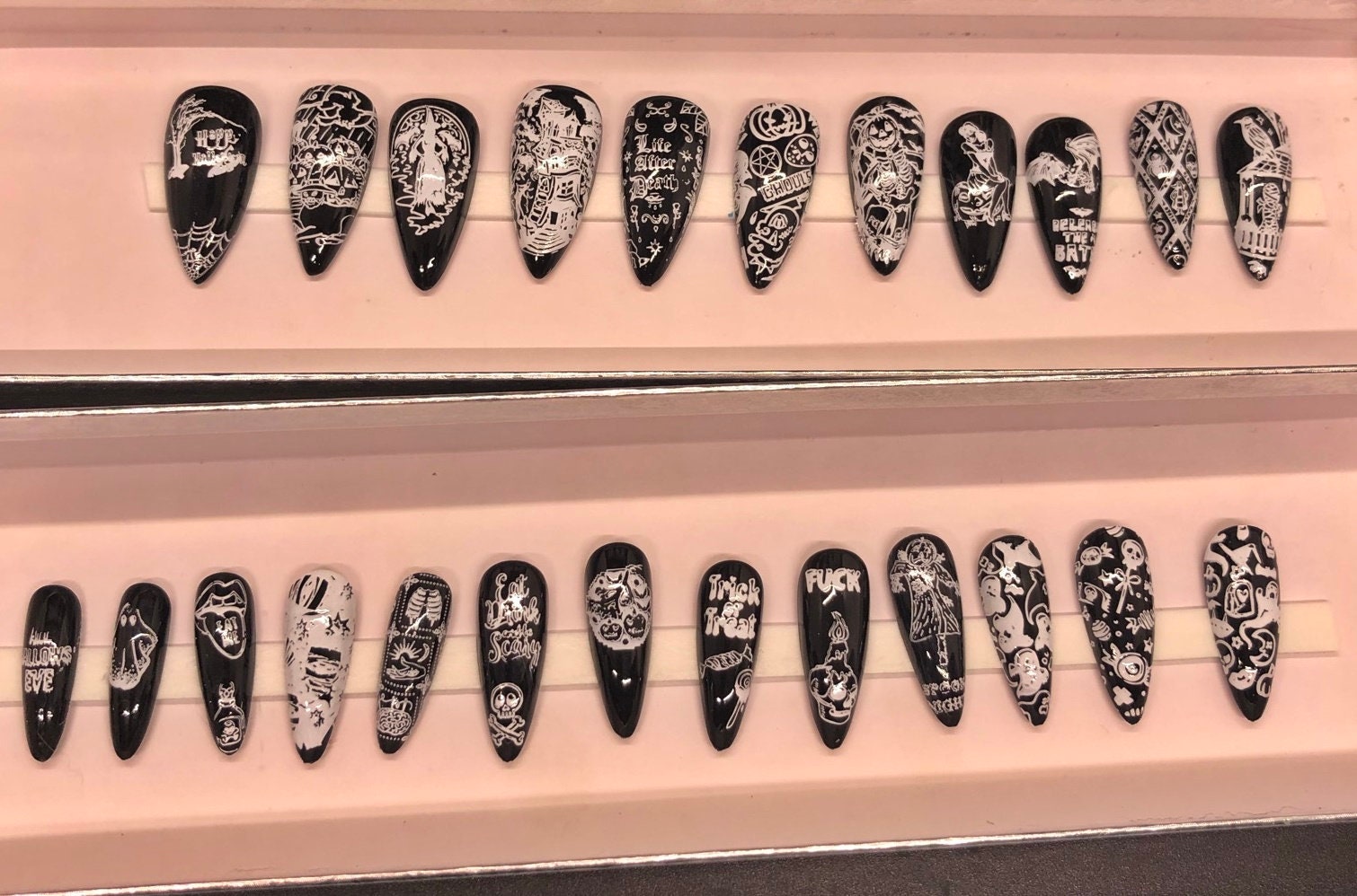 A set of 24 Halloween themed press on nails in stiletto, coffin, and short styles, showcasing various spooky designs.