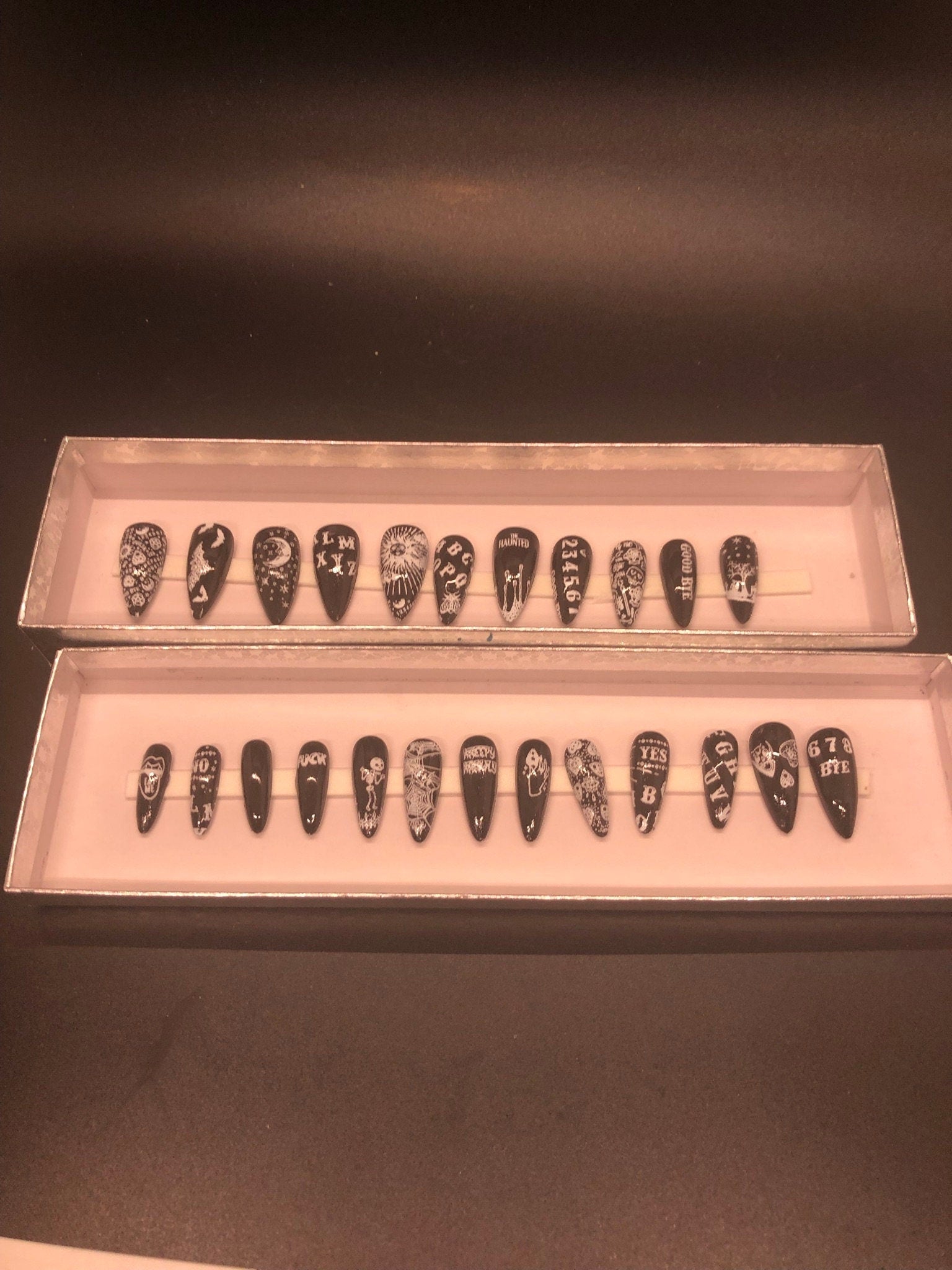 A set of 24 Ouija Board themed press on nails in stiletto, coffin, and short styles, showcasing unique designs and colors.