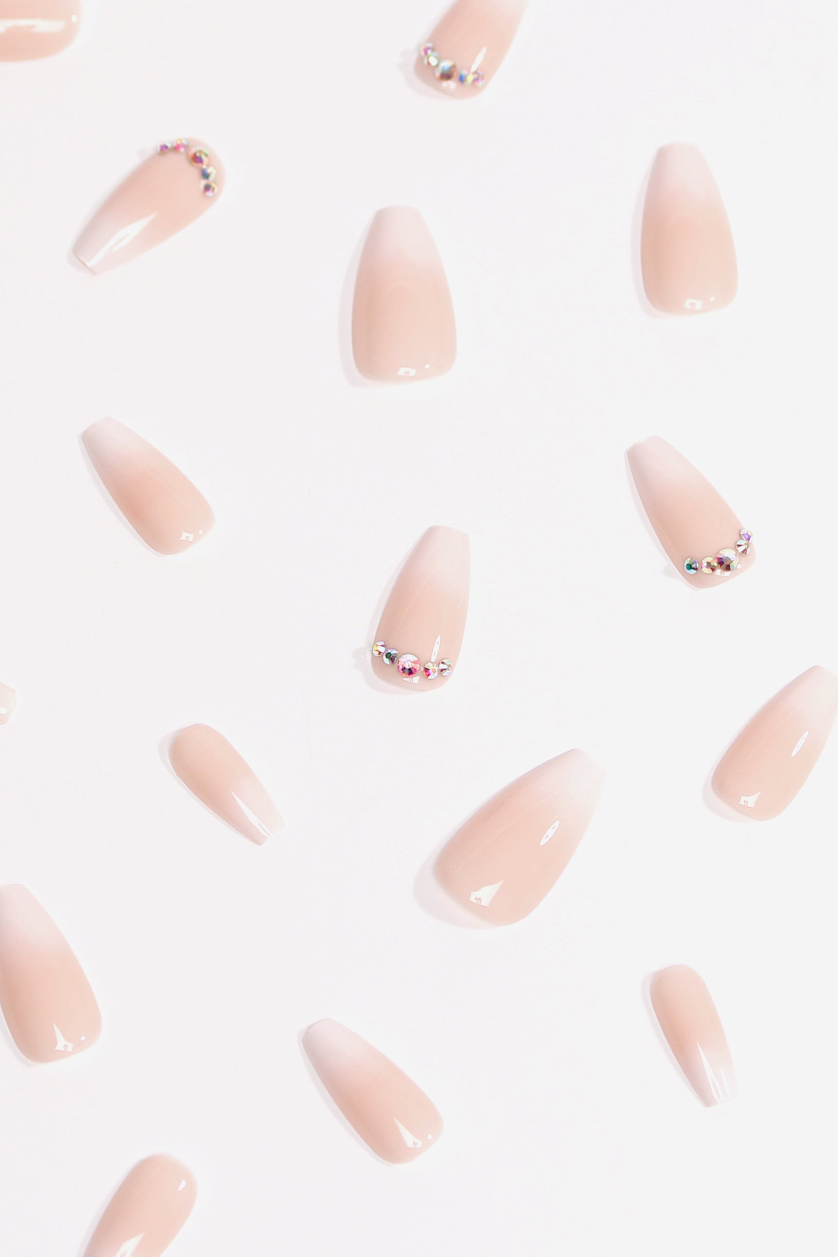 Strawberry Mousse press-on nails featuring a creamy hue and sparkling rhinestone tips, elegantly arranged for a polished look.