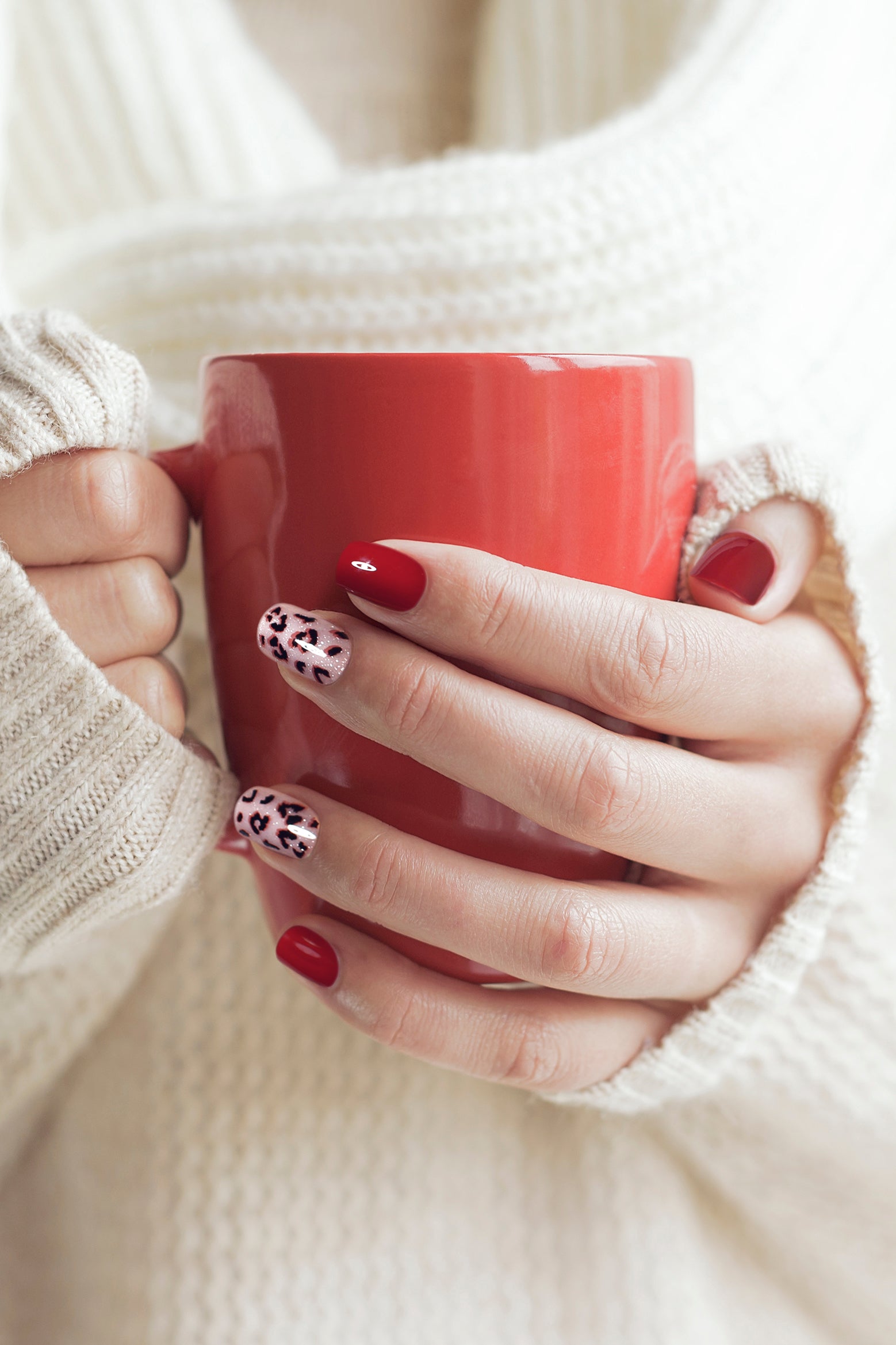 Wild Romance press-on nails featuring deep red color with leopard spots on a shimmering background, showcasing elegance and boldness.