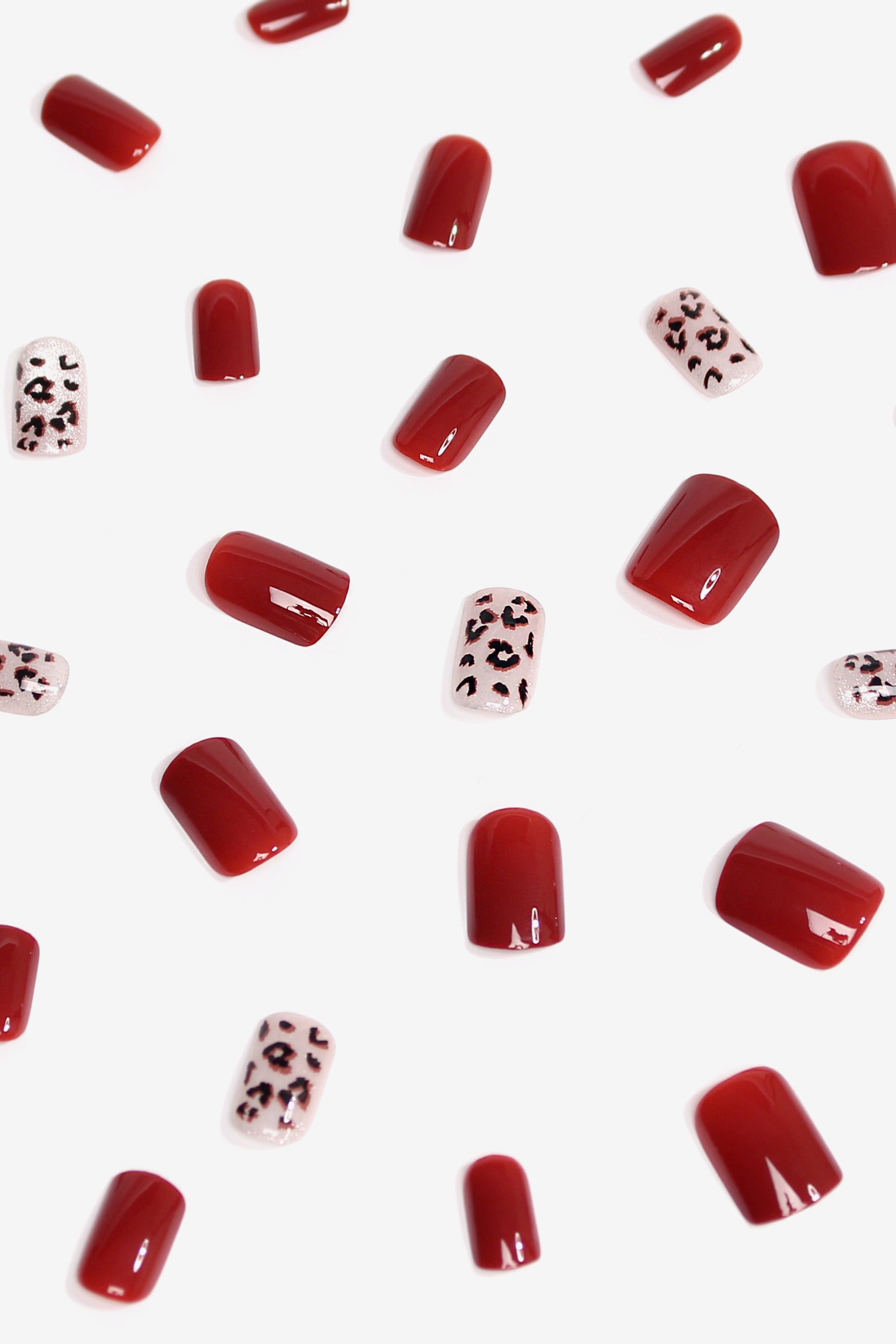 Wild Romance press-on nails featuring deep red color with leopard spots on a shimmering background, showcasing elegance and boldness.