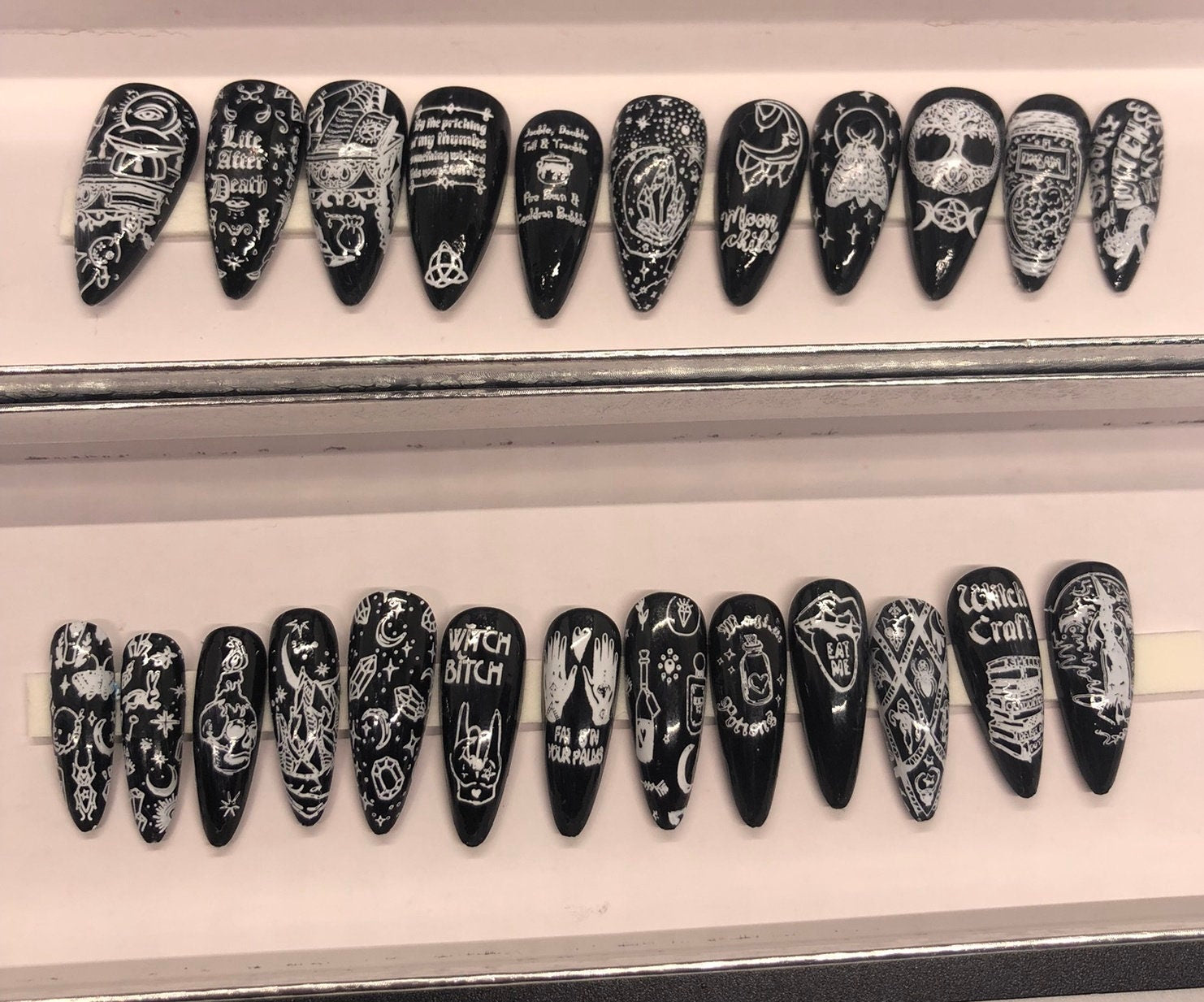 A set of 24 witch-themed press on nails in various styles including stiletto, coffin, and short, showcasing unique designs and colors.