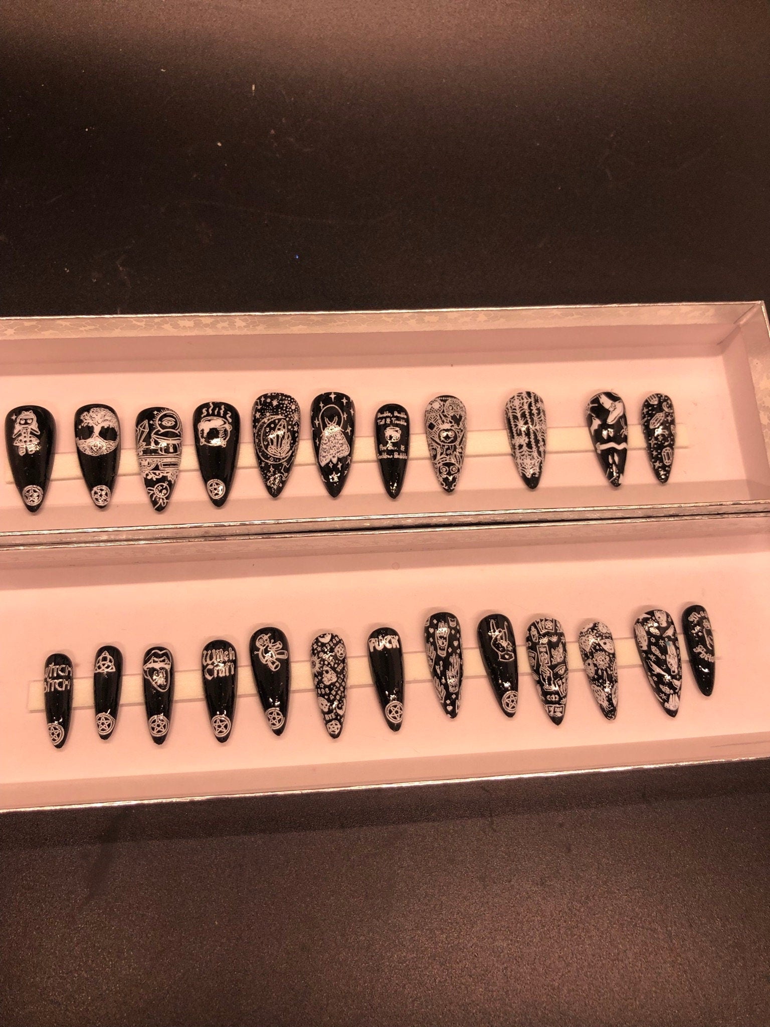 A set of 24 witch-themed press on nails in various styles including stiletto, coffin, and short, showcasing unique designs and colors.