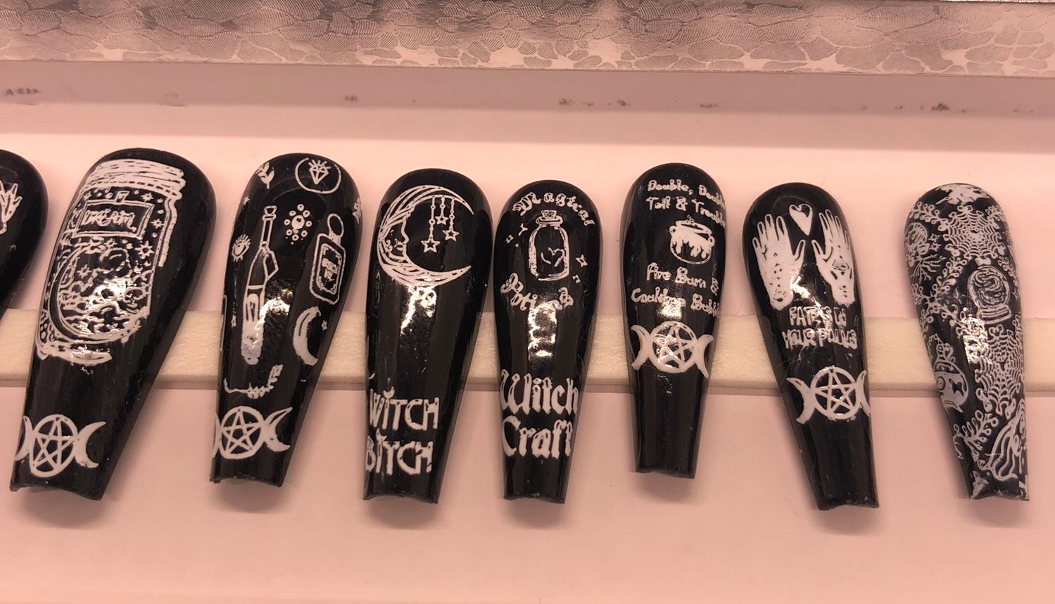 A set of 24 witch-themed press on nails in various styles including stiletto, coffin, and short, showcasing unique designs and colors.