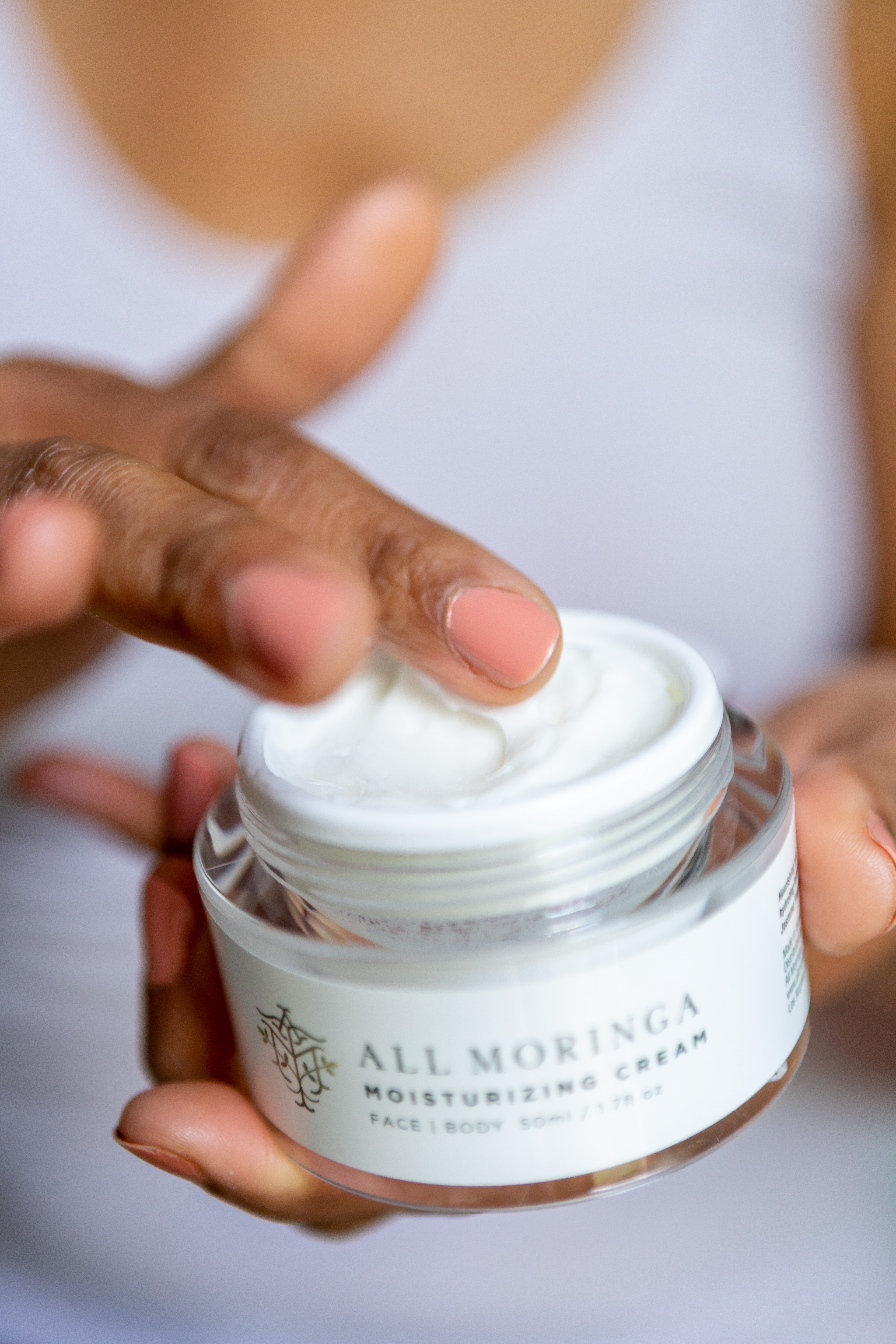 A jar of unique Moringa Moisturizing Face Cream with a soft, silky texture, showcasing its natural ingredients and white color.