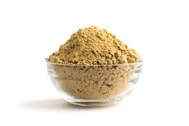 A bowl of organic African Ginger Root Powder with fresh ginger roots in the background, showcasing its rich color and texture.