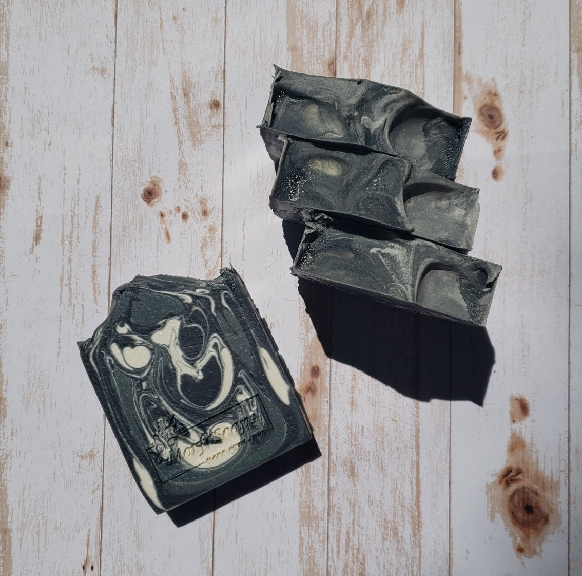 A bar of MorfoSoaps' All Natural Eucalyptus Soap, showcasing its unique color and texture, made with eucalyptus oil and activated charcoal.