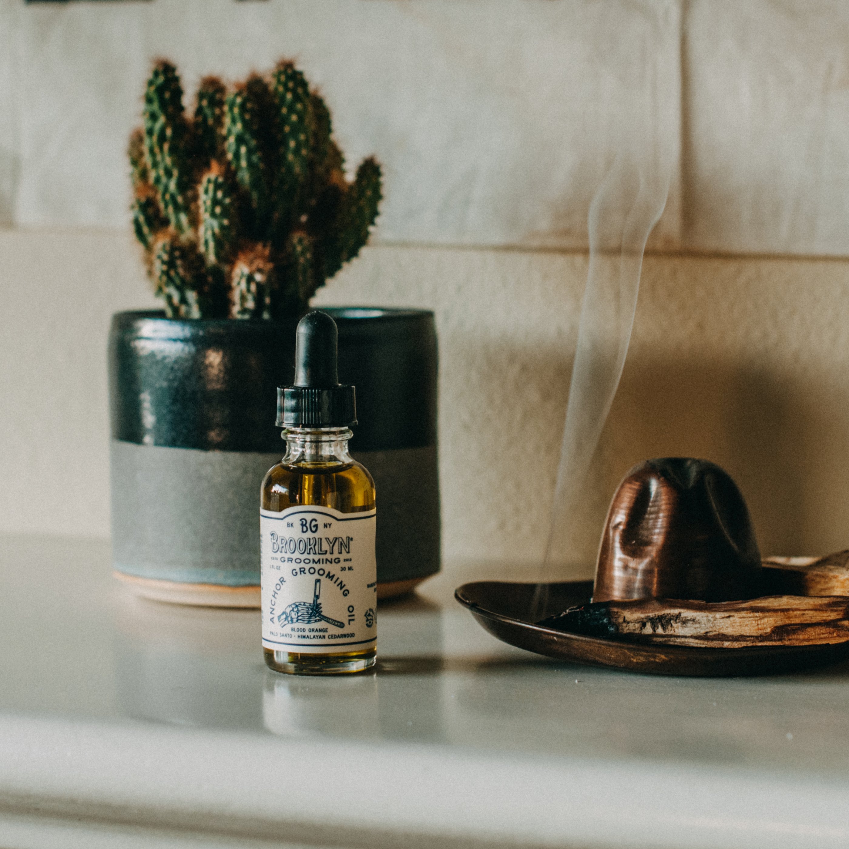 Bottle of Anchor Grooming Oil with a dropper, showcasing its light golden color and elegant design, set against a neutral background.