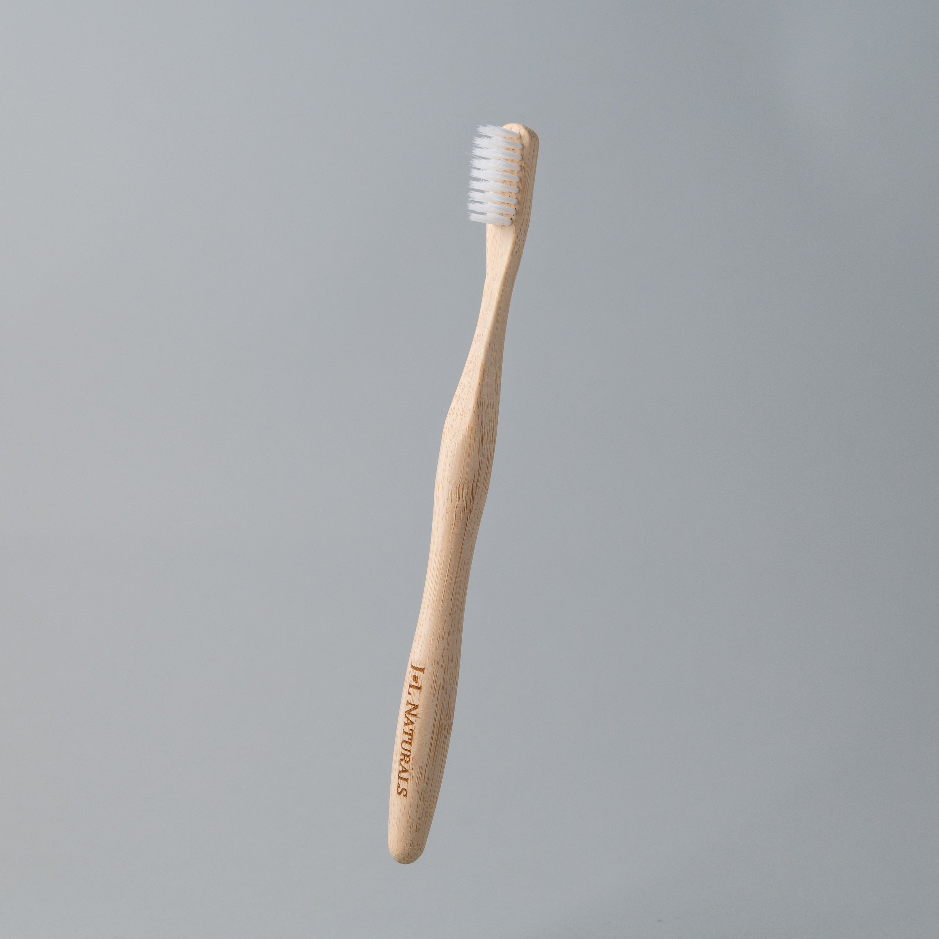 A bamboo toothbrush with medium wavy bristles and an ergonomic handle, available in various colors including black, white, natural, and rainbow.