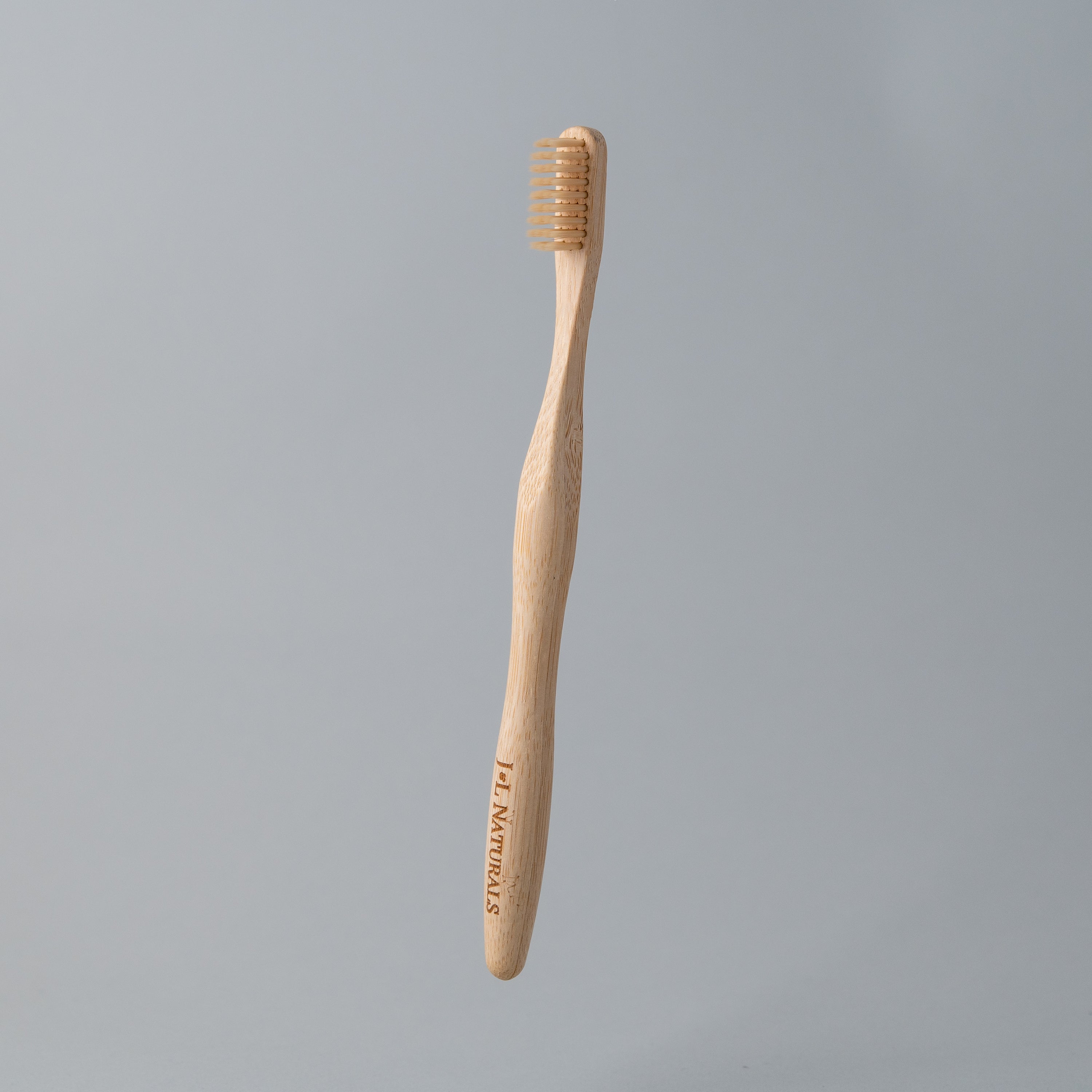 A bamboo toothbrush with medium wavy bristles and an ergonomic handle, available in various colors including black, white, natural, and rainbow.