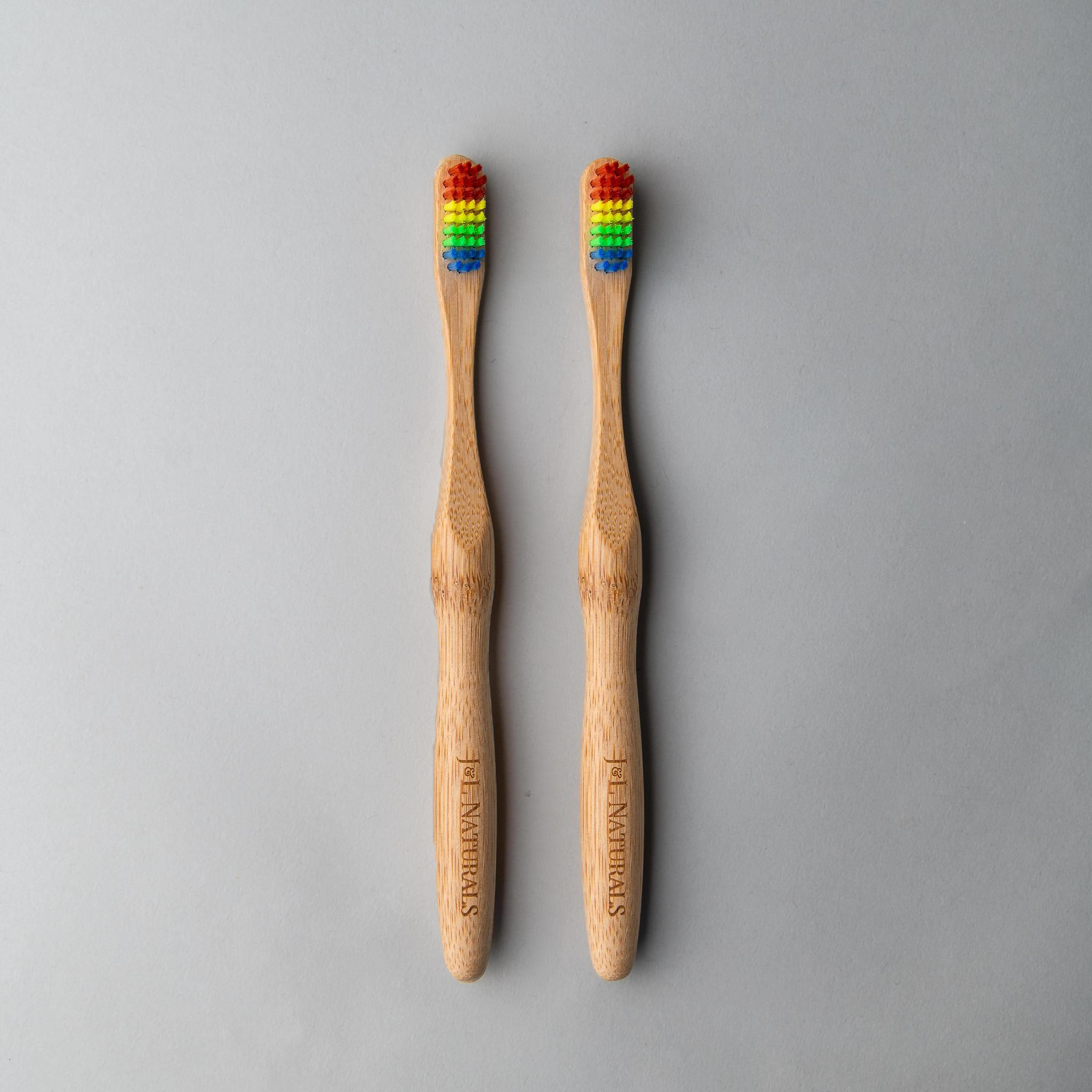 Two bamboo toothbrushes with ergonomic handles and medium wavy bristles, available in various colors.