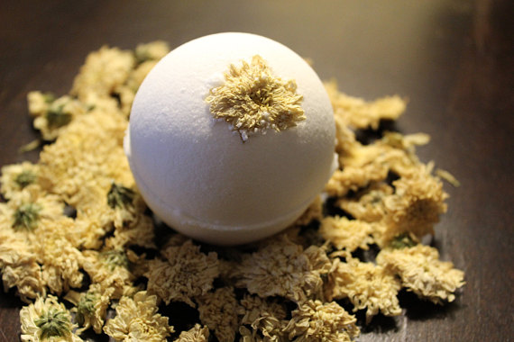 Sleepy Baby Bath Bomb with lavender and chamomile, topped with a dried chrysanthemum flower, in a relaxing bath setting.