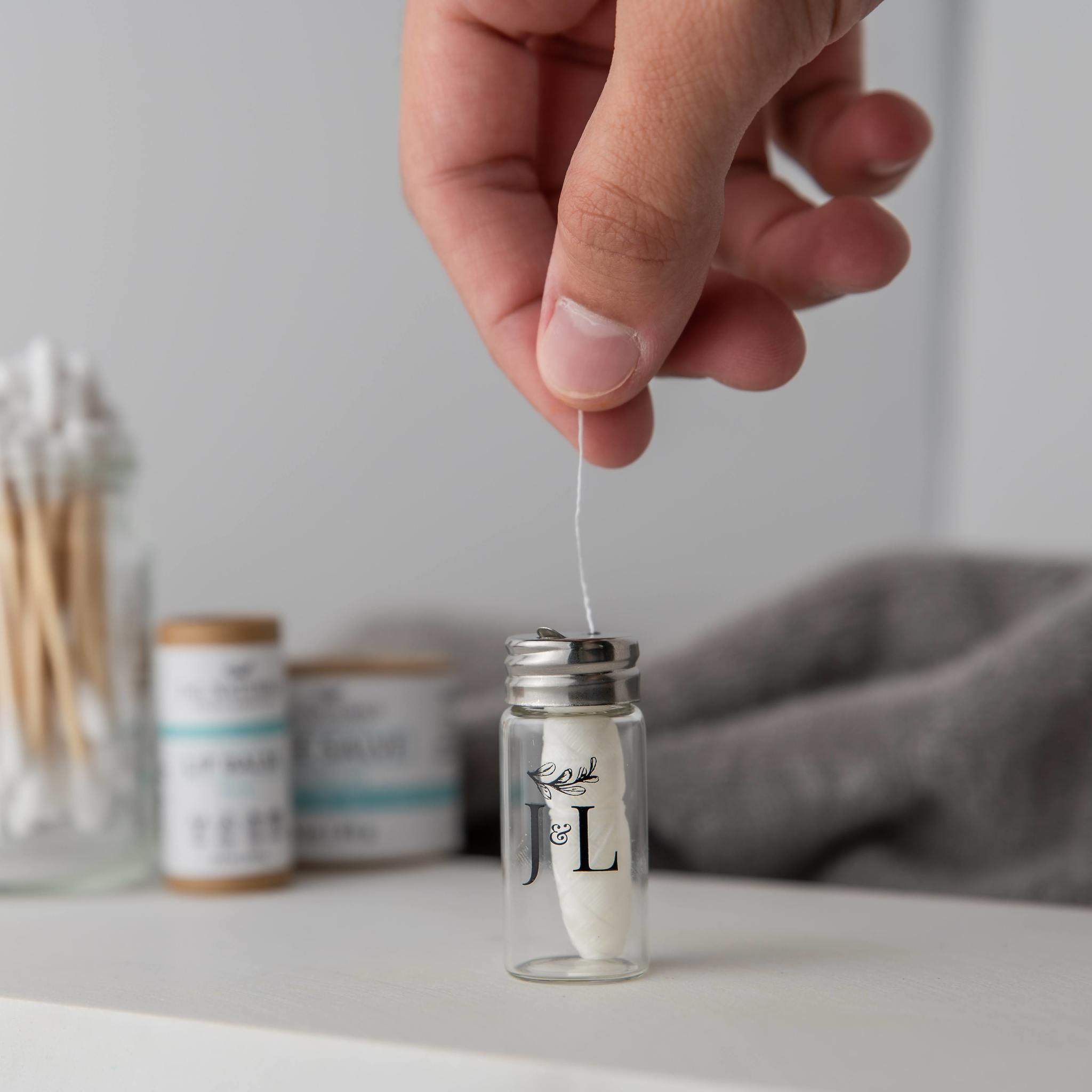 Hand holding container with floss.