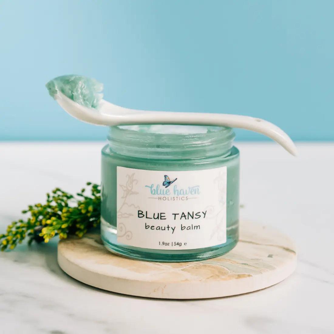 Blue Tansy Beauty Balm in a jar, showcasing its rich, creamy texture and vibrant blue color, surrounded by natural ingredients.