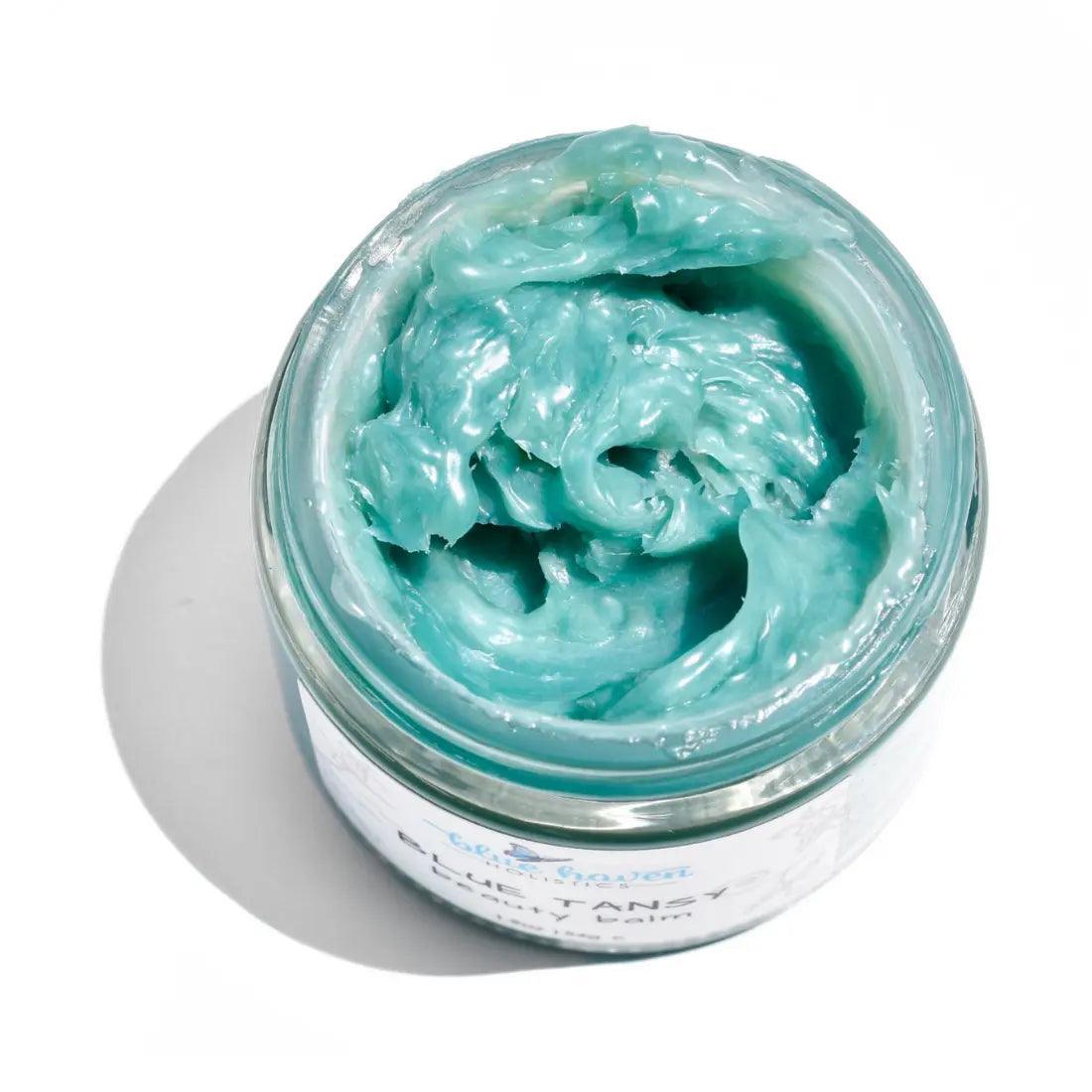 Blue Tansy Beauty Balm in a jar, showcasing its rich, creamy texture and vibrant blue color, surrounded by natural ingredients.