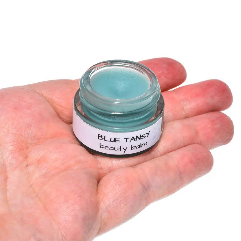 Blue Tansy Beauty Balm in a jar, showcasing its rich, creamy texture and vibrant blue color, surrounded by natural ingredients.