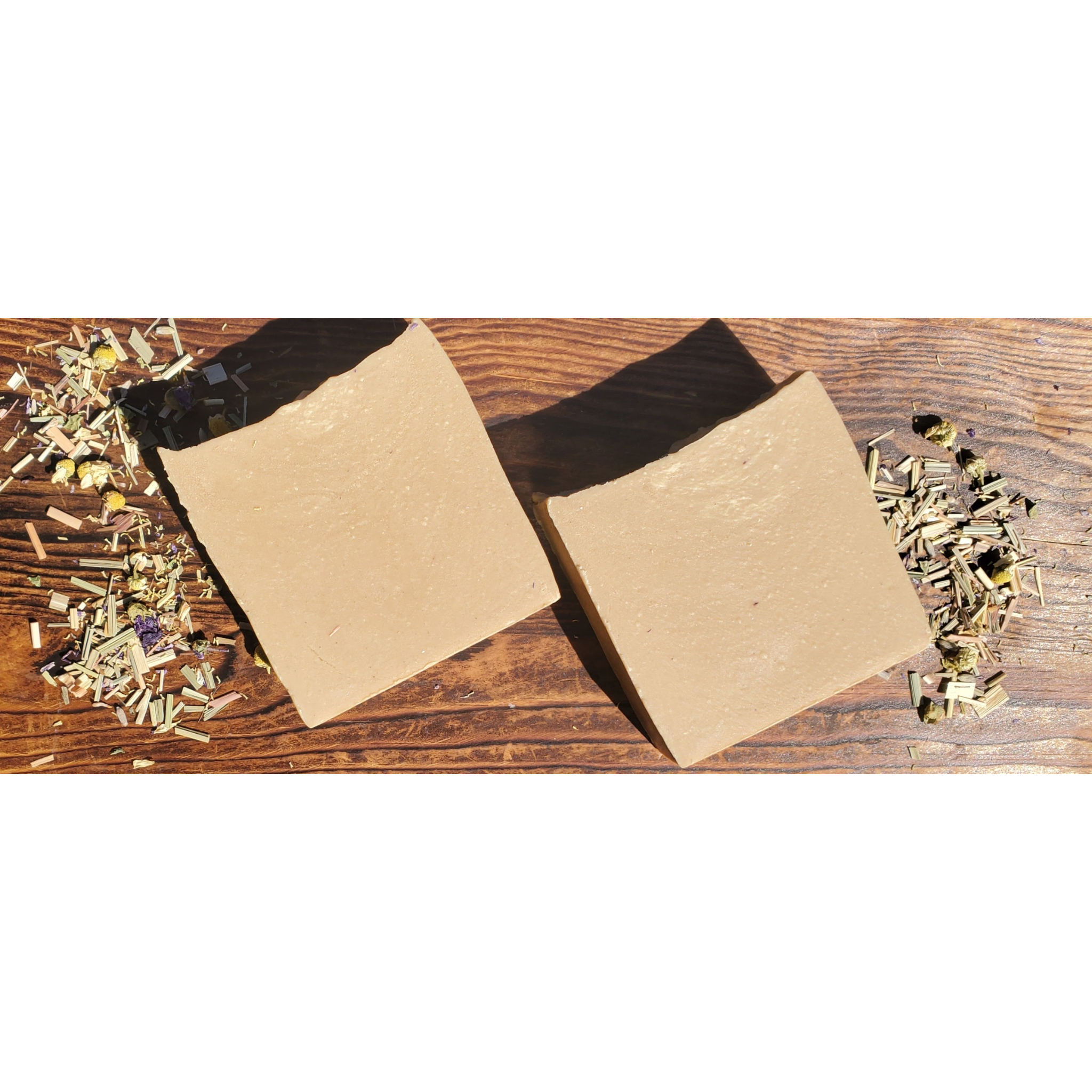 A bar of Calendula & Chamomile Soap with chamomile flowers and calendula petals, showcasing its natural ingredients and artisan quality.