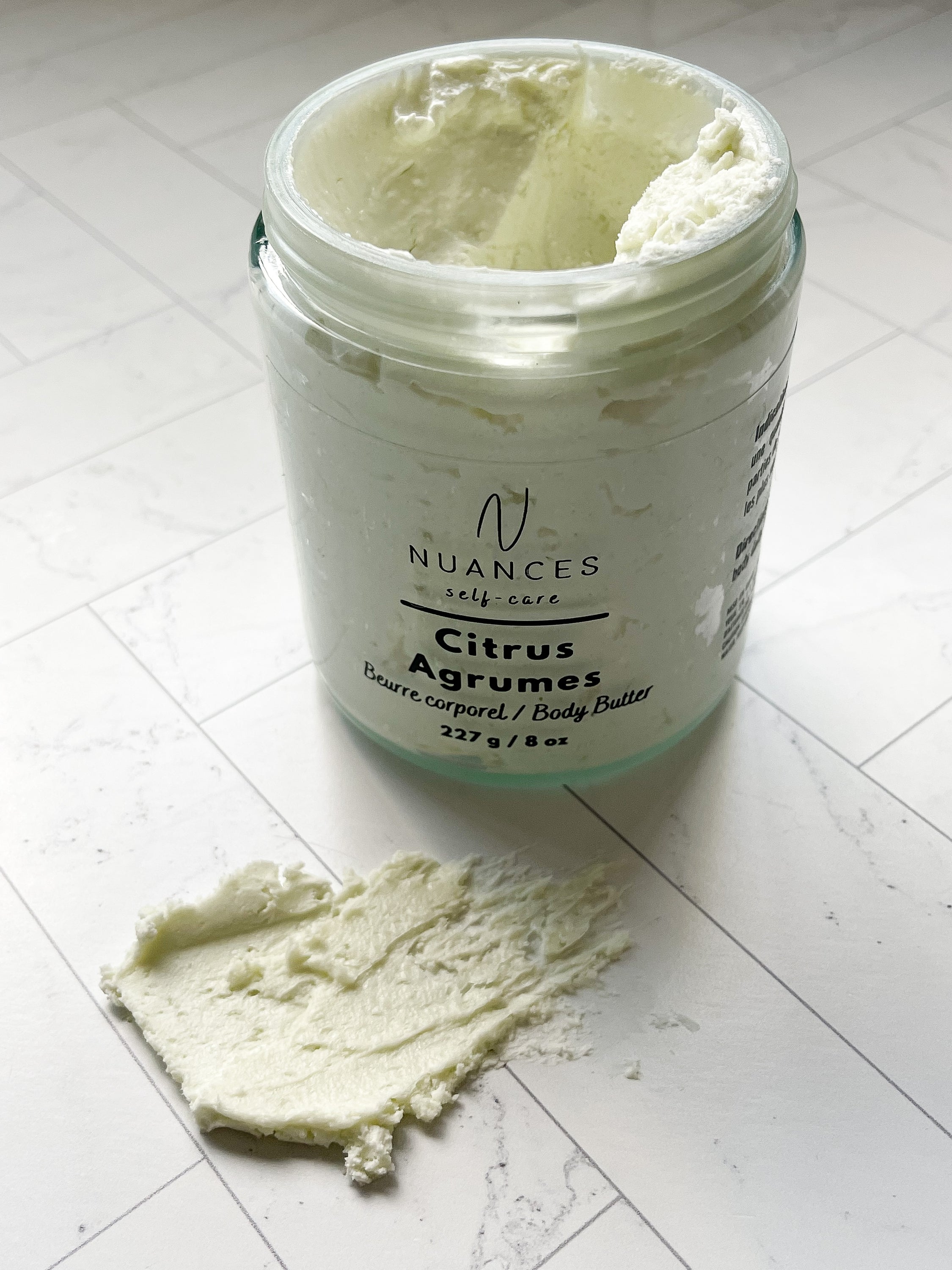 A jar of Citrus Body Butter with a vibrant citrus scent, showcasing its creamy texture and rich ingredients like mango butter and grape seed oil.