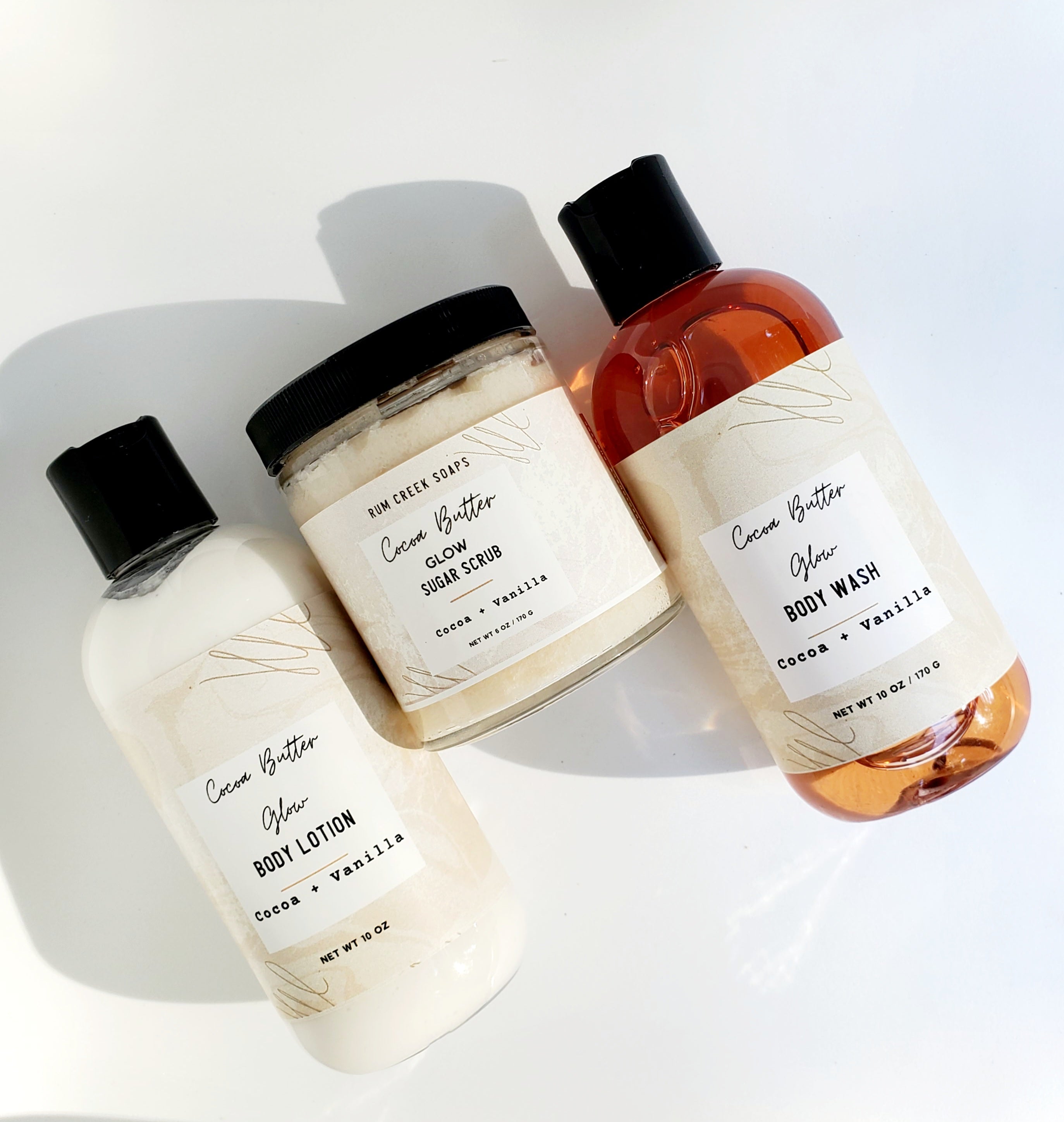 Cocoa Butter Glow Skincare Set including body wash, lotion, and sugar scrub in elegant packaging, showcasing a rich cocoa butter theme.