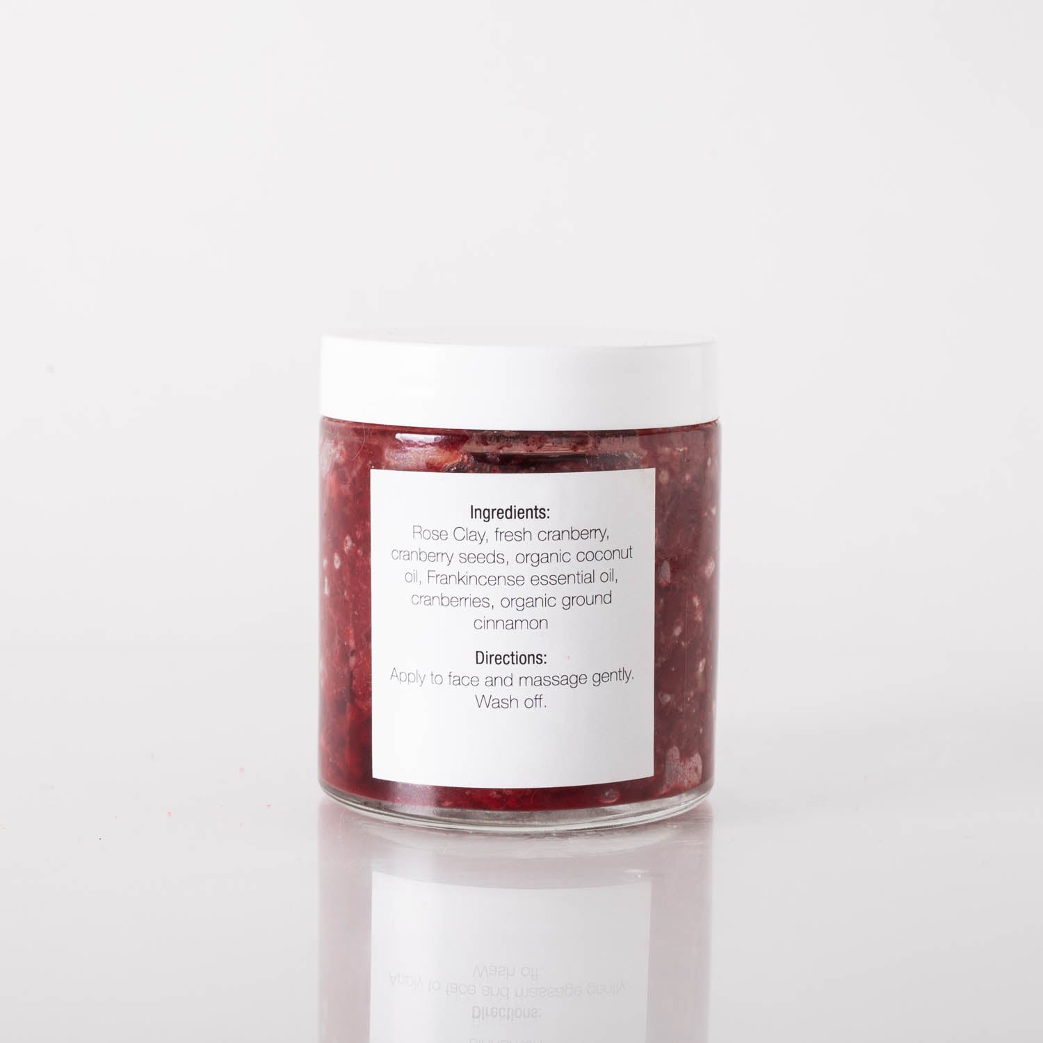 Cranberry Seed Brightening Face Scrub in a jar with cranberries and natural ingredients around it, showcasing its exfoliating properties.