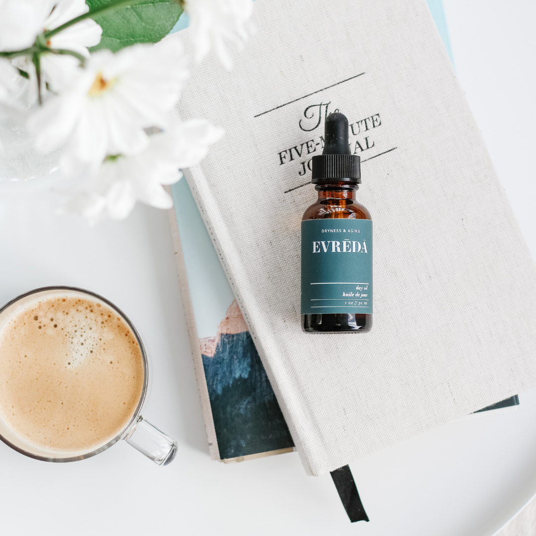 A bottle of Dryness & Aging Day Oil featuring a sleek design, showcasing its rich, golden oil inside, surrounded by natural ingredients like apricot kernels and camellia flowers.