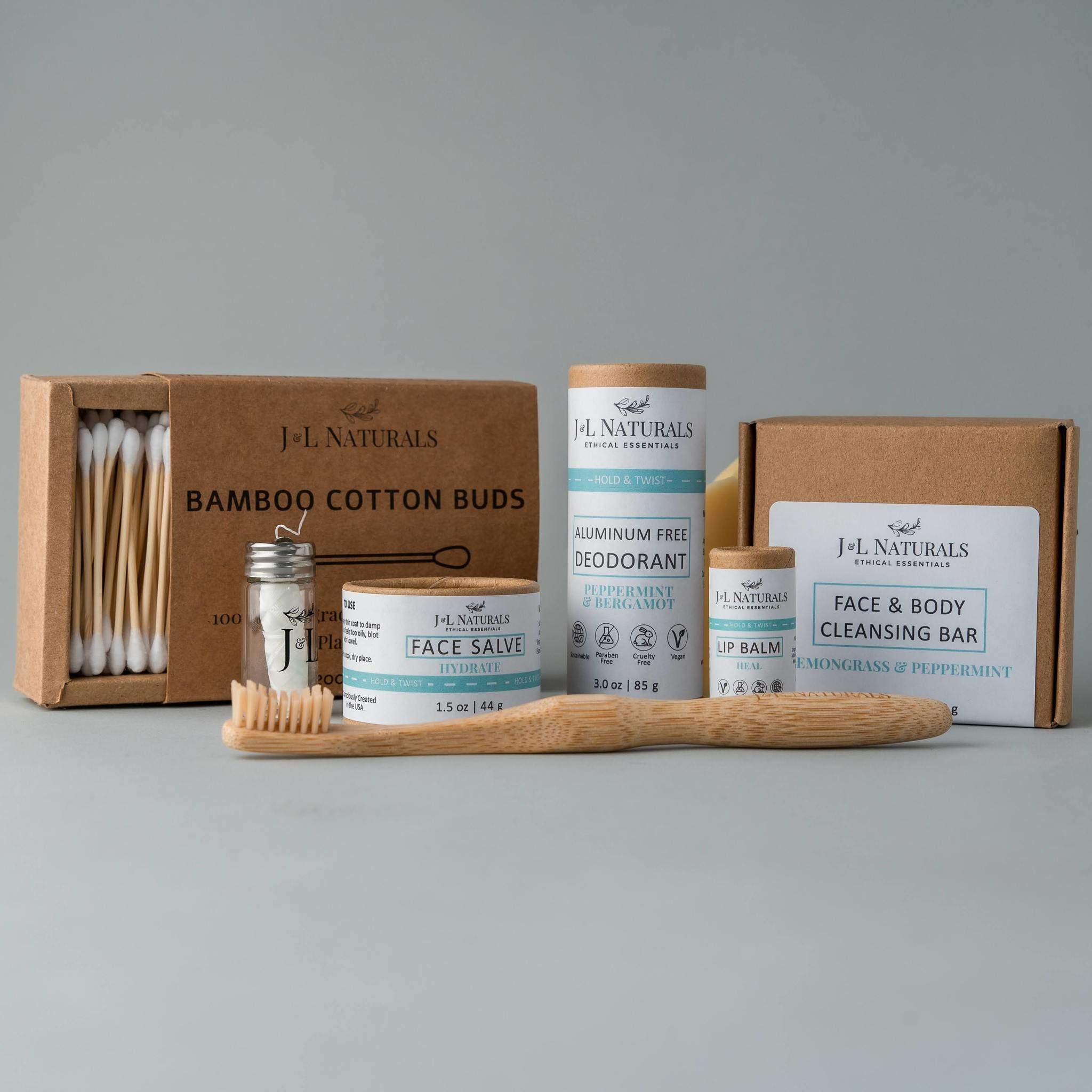 Essentials Self Care Kit featuring 7 skincare products including cleansing bar, face salve, lip balm, deodorant, bamboo toothbrush, floss, and cotton buds.