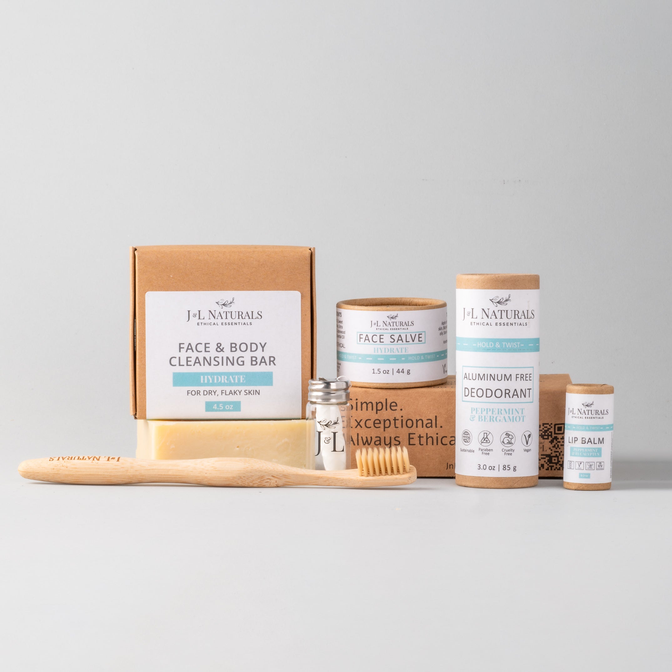 Essentials Self Care Kit featuring 7 skincare products including cleansing bar, face salve, lip balm, deodorant, bamboo toothbrush, floss, and cotton buds.