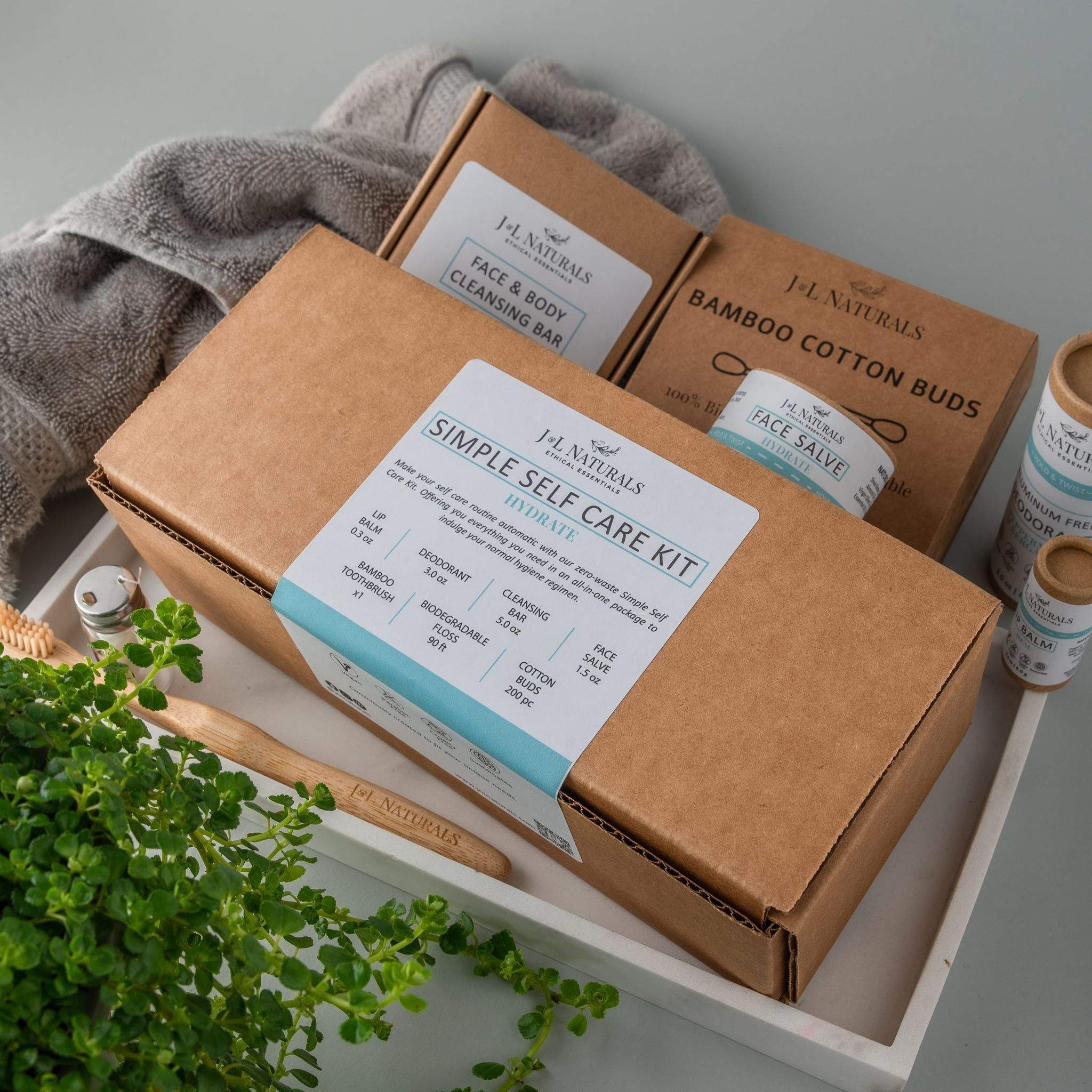 Essentials Self Care Kit featuring 7 skincare products including cleansing bar, face salve, lip balm, deodorant, bamboo toothbrush, floss, and cotton buds.