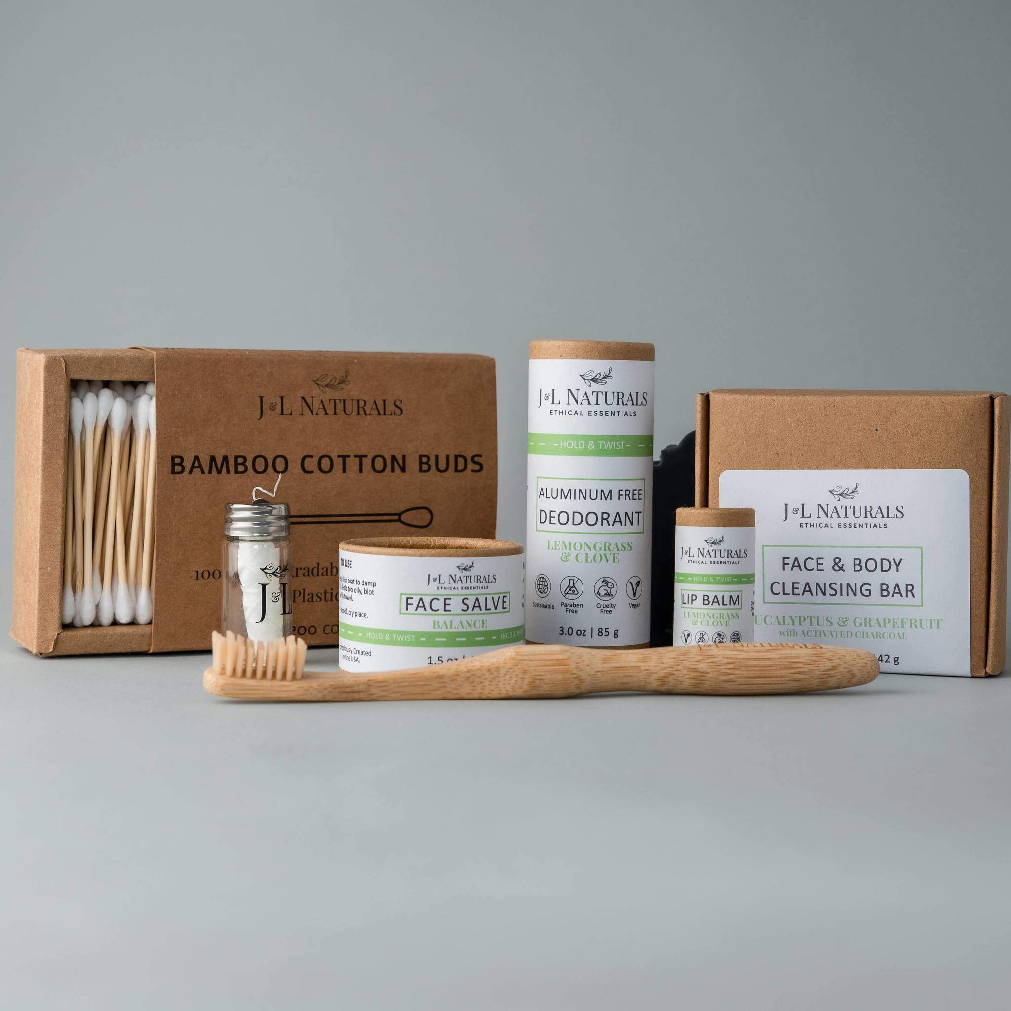 Essentials Self Care Kit featuring 7 skincare products including cleansing bar, face salve, lip balm, deodorant, bamboo toothbrush, floss, and cotton buds.