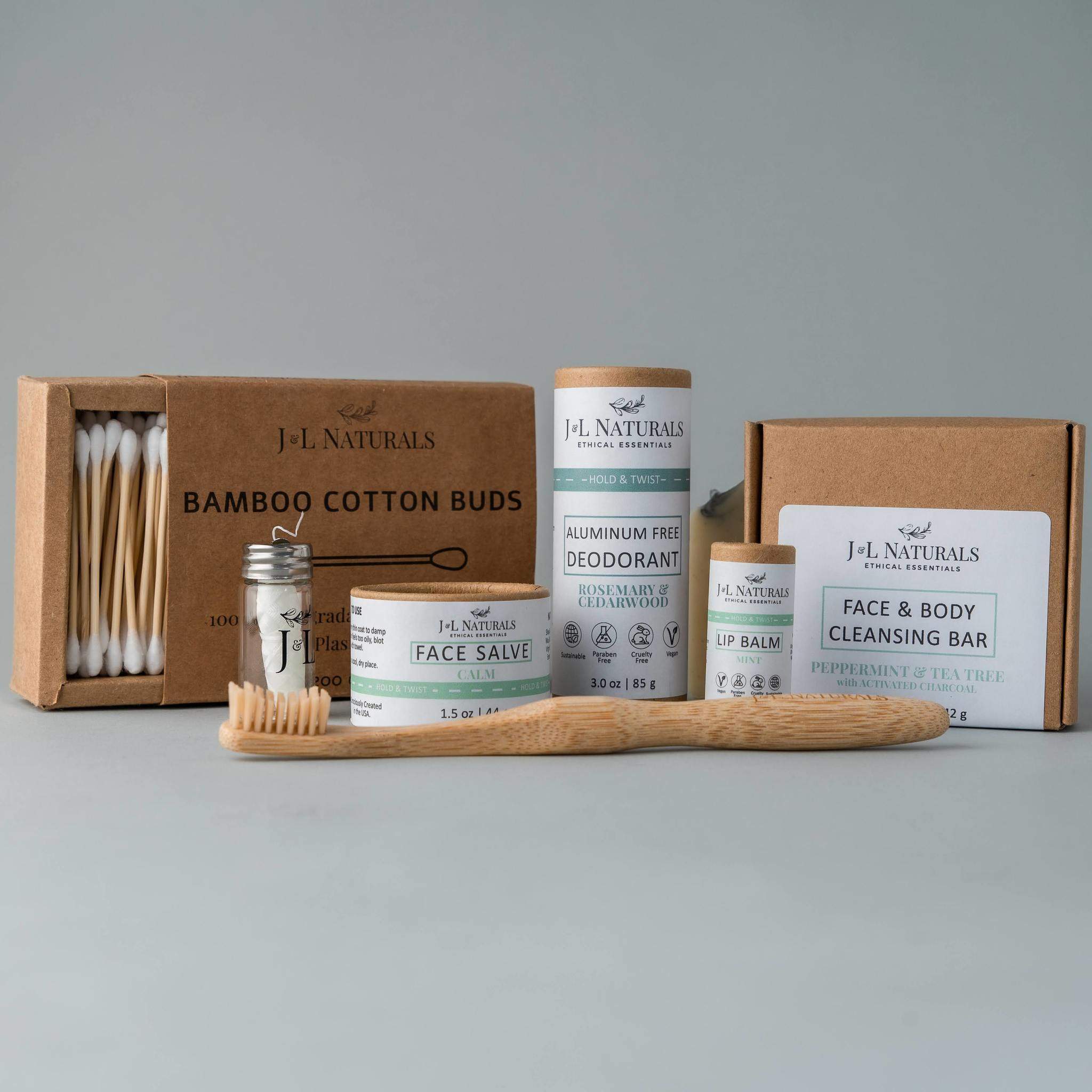 Essentials Self Care Kit featuring 7 skincare products including cleansing bar, face salve, lip balm, deodorant, bamboo toothbrush, floss, and cotton buds.