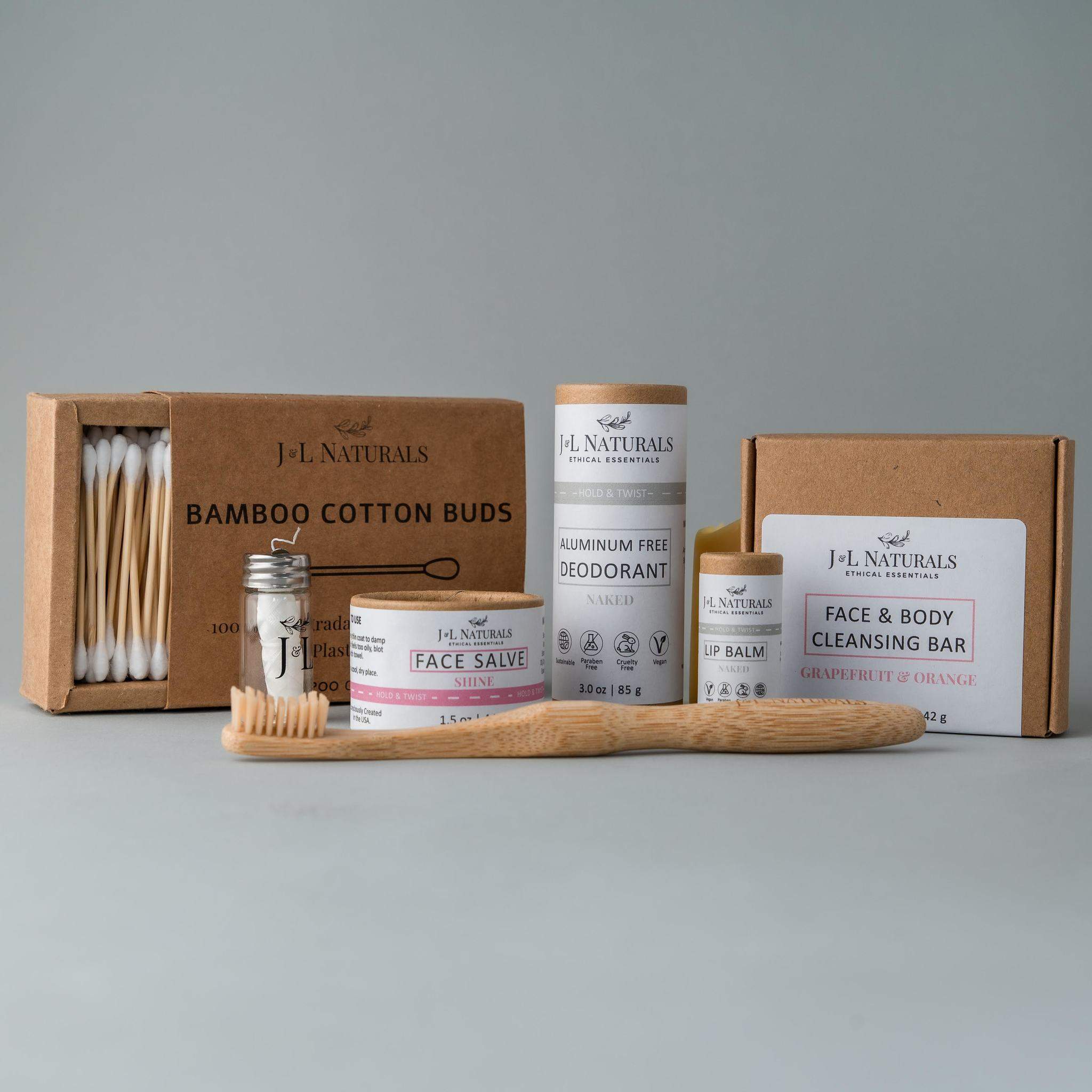 Essentials Self Care Kit featuring 7 skincare products including cleansing bar, face salve, lip balm, deodorant, bamboo toothbrush, floss, and cotton buds.