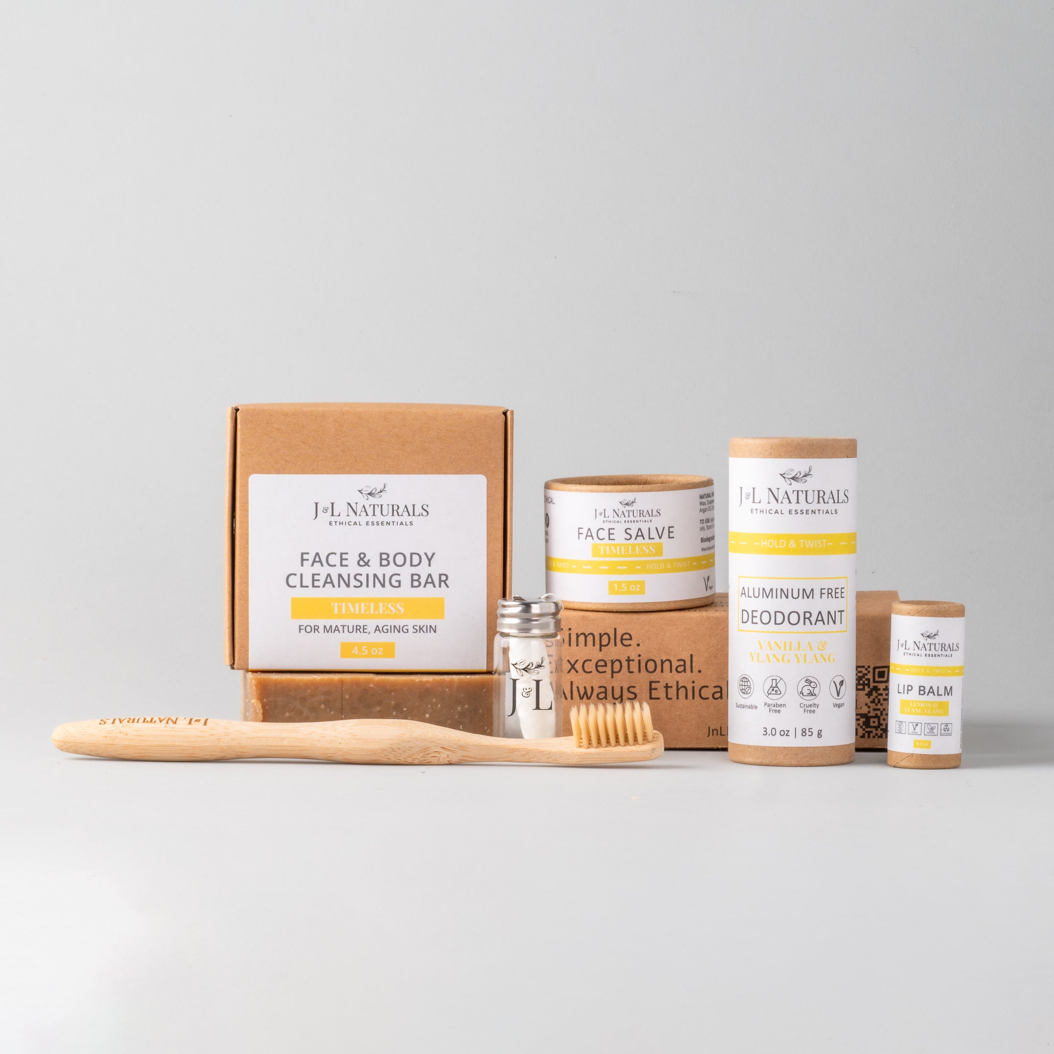 Essentials Self Care Kit featuring 7 skincare products including cleansing bar, face salve, lip balm, deodorant, bamboo toothbrush, floss, and cotton buds.