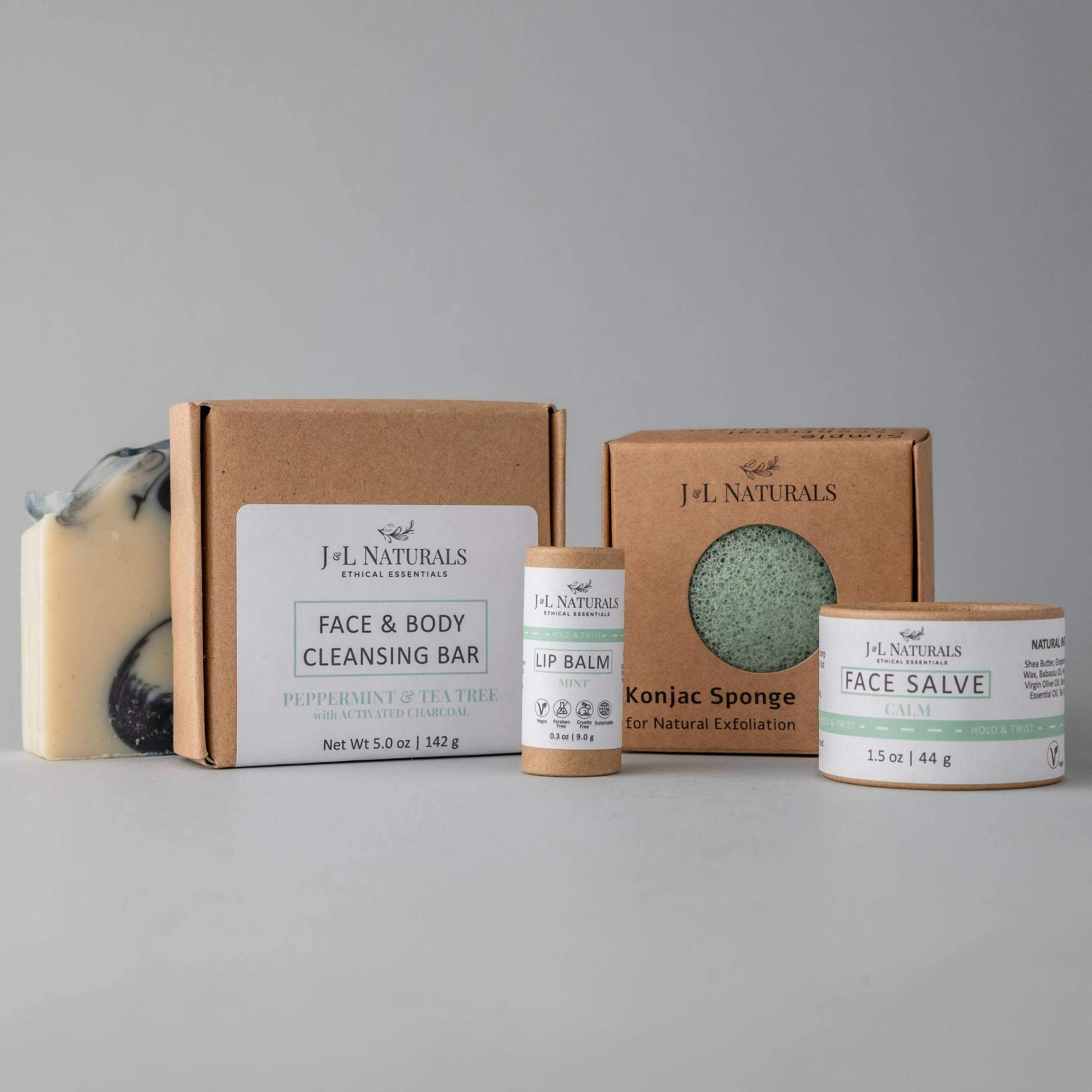 Essentials Skin Regimen Kit featuring a cleansing bar, konjac sponge, face salve, and lip balm in a stylish packaging.