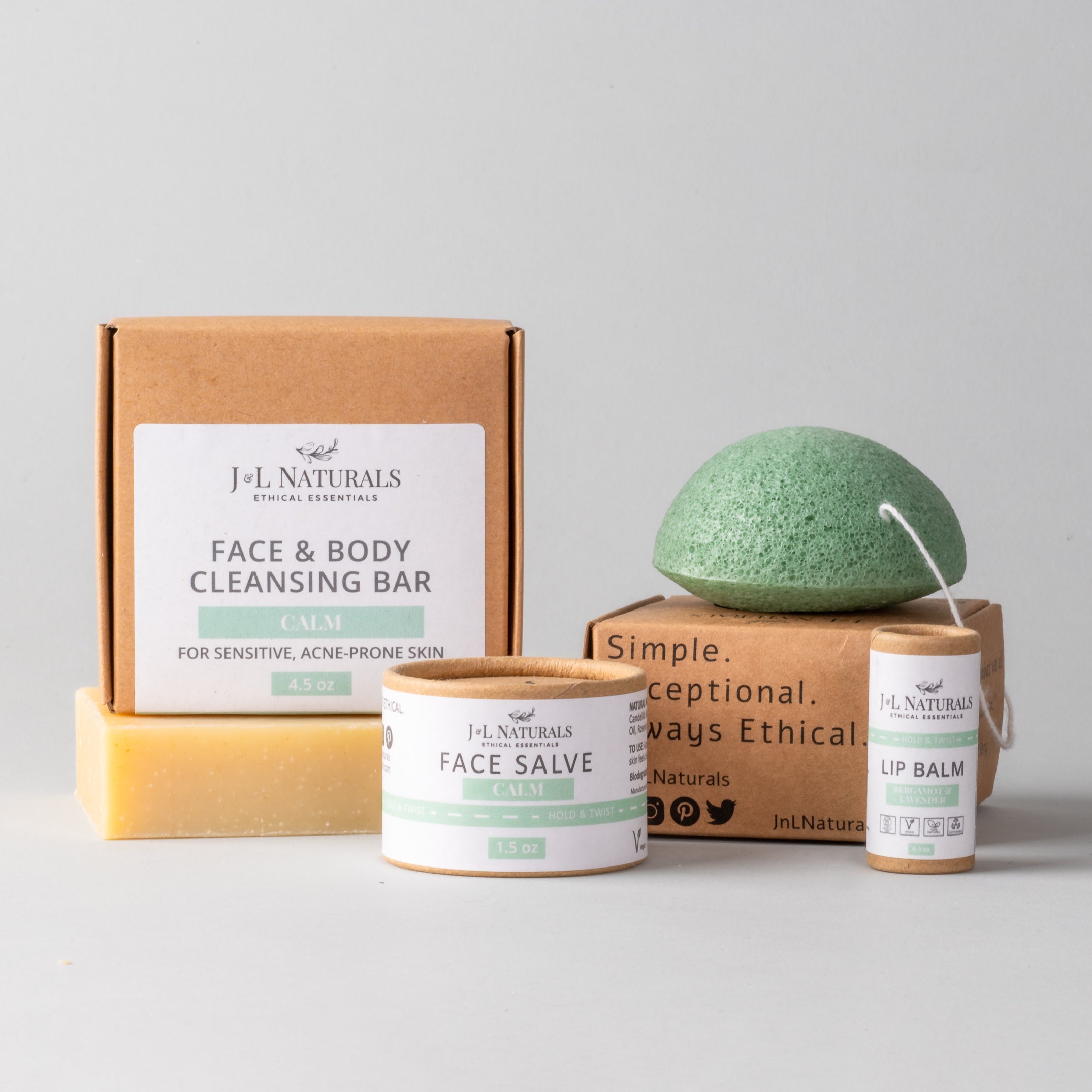 Essentials Skin Regimen Kit featuring a cleansing bar, konjac sponge, face salve, and lip balm in a stylish packaging.