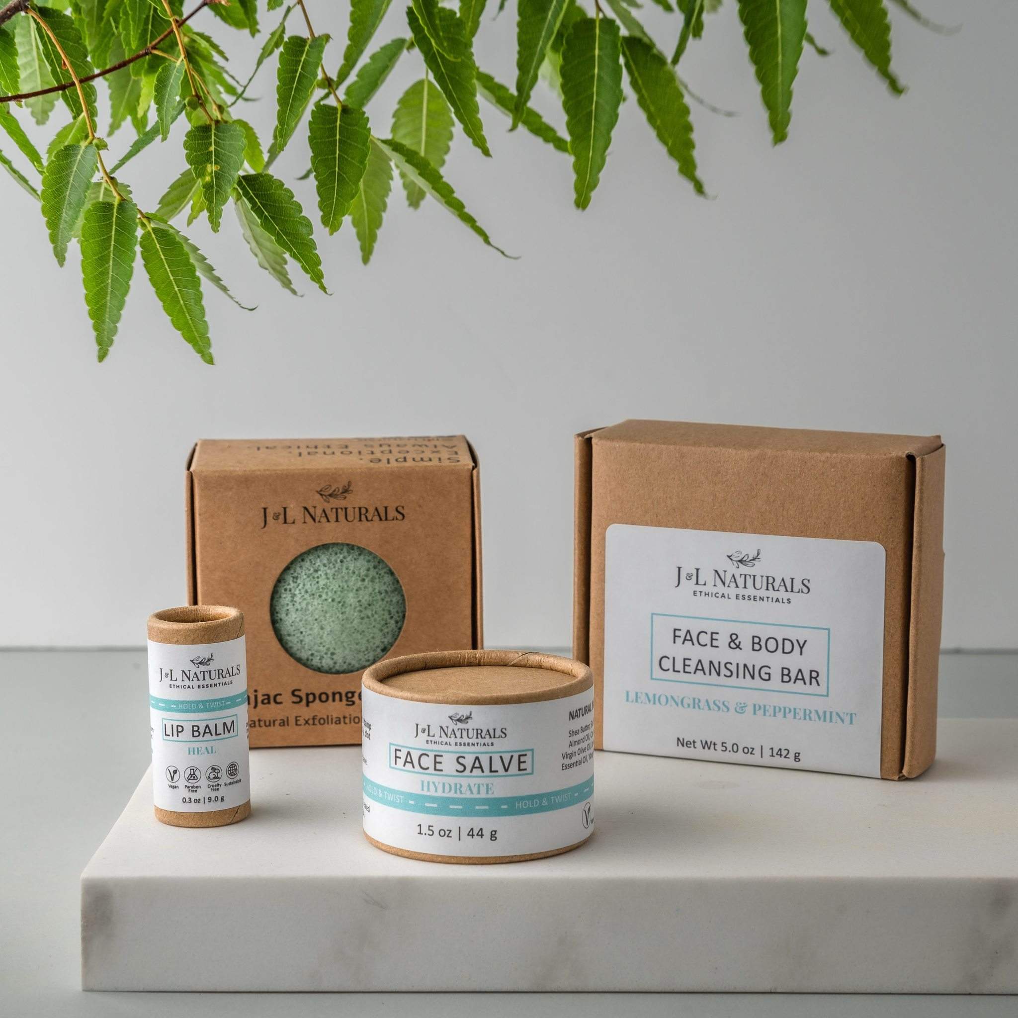 Essentials Skin Regimen Kit featuring a cleansing bar, konjac sponge, face salve, and lip balm in a stylish packaging.