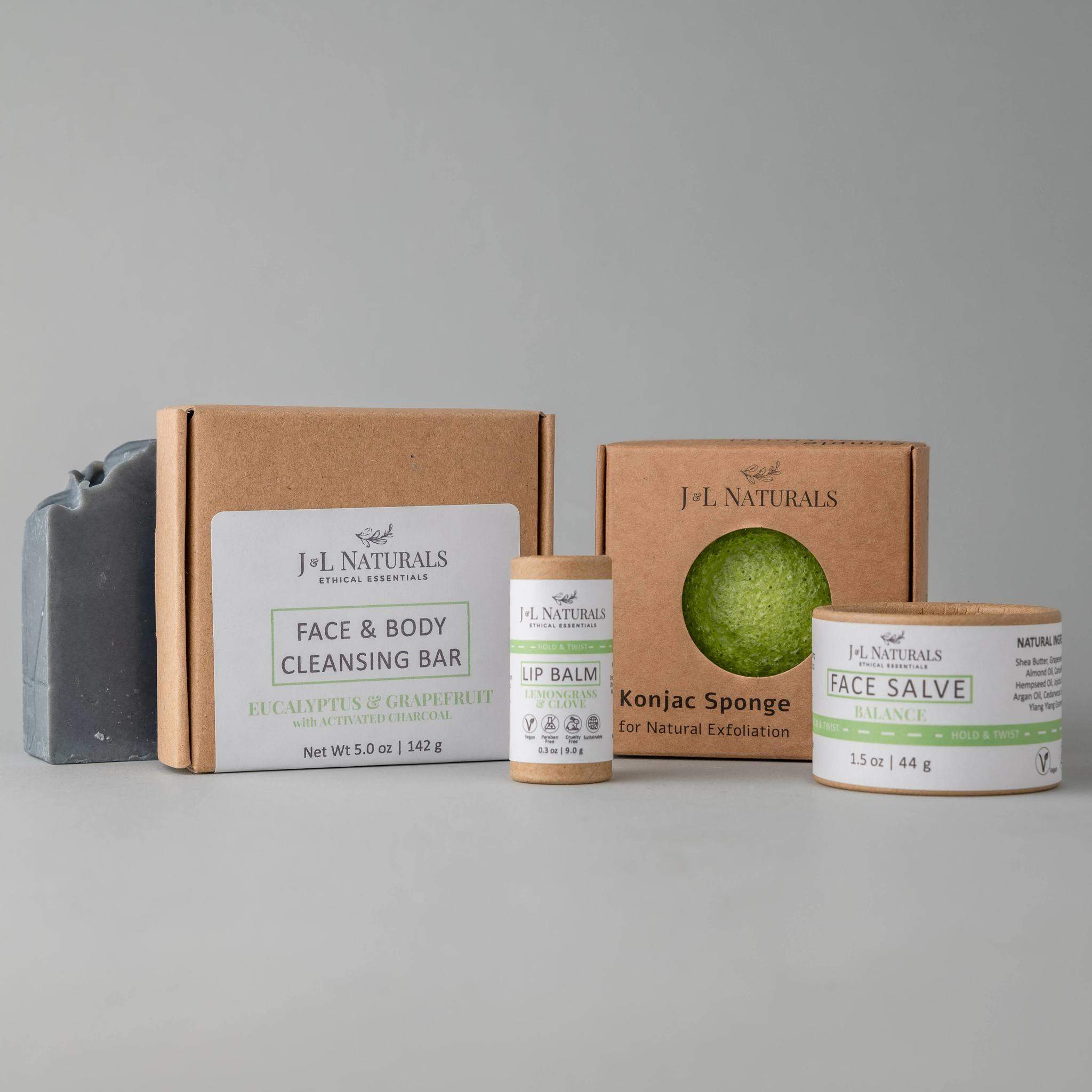 Essentials Skin Regimen Kit featuring a cleansing bar, konjac sponge, face salve, and lip balm in a stylish packaging.