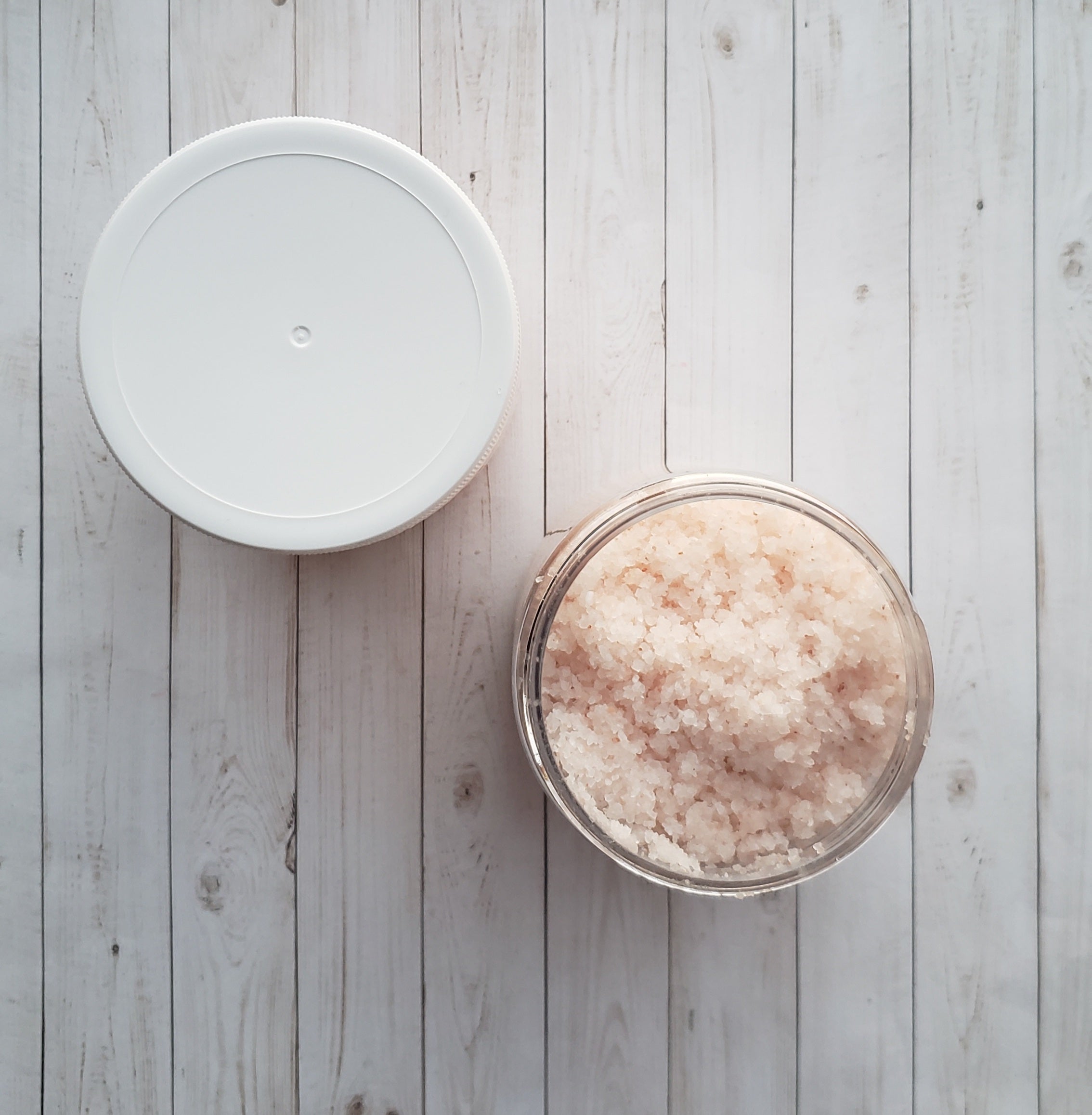 A jar of Eucalyptus Bath Salt with eucalyptus leaves and a wooden scoop, showcasing its natural ingredients and soothing properties.