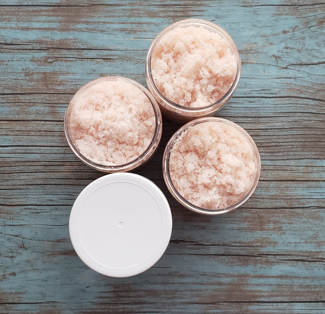 A jar of Eucalyptus Bath Salt with eucalyptus leaves and a wooden scoop, showcasing its natural ingredients and soothing properties.