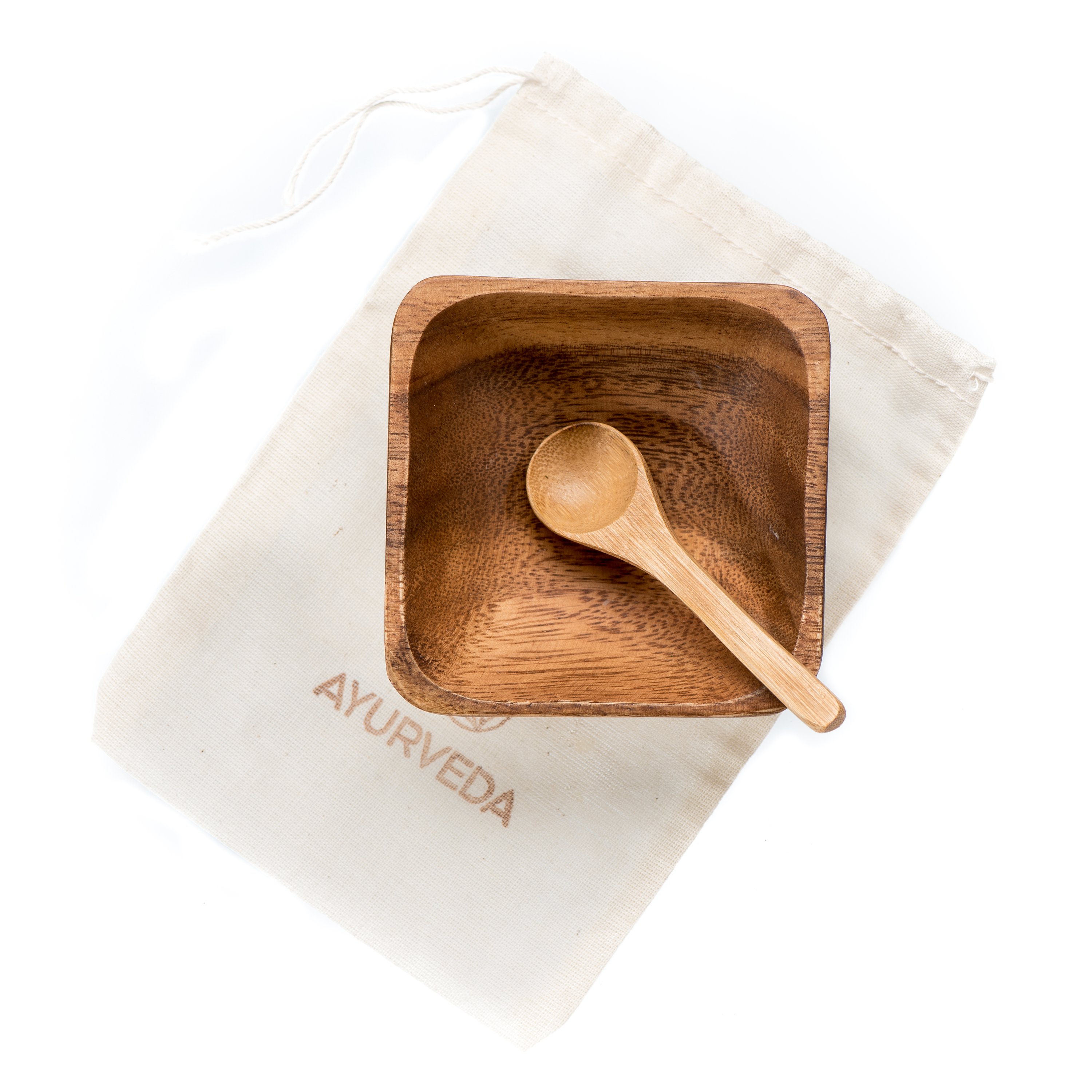 Eco-friendly bamboo spoon and acacia bowl for mixing skincare products, accompanied by a muslin travel pouch.