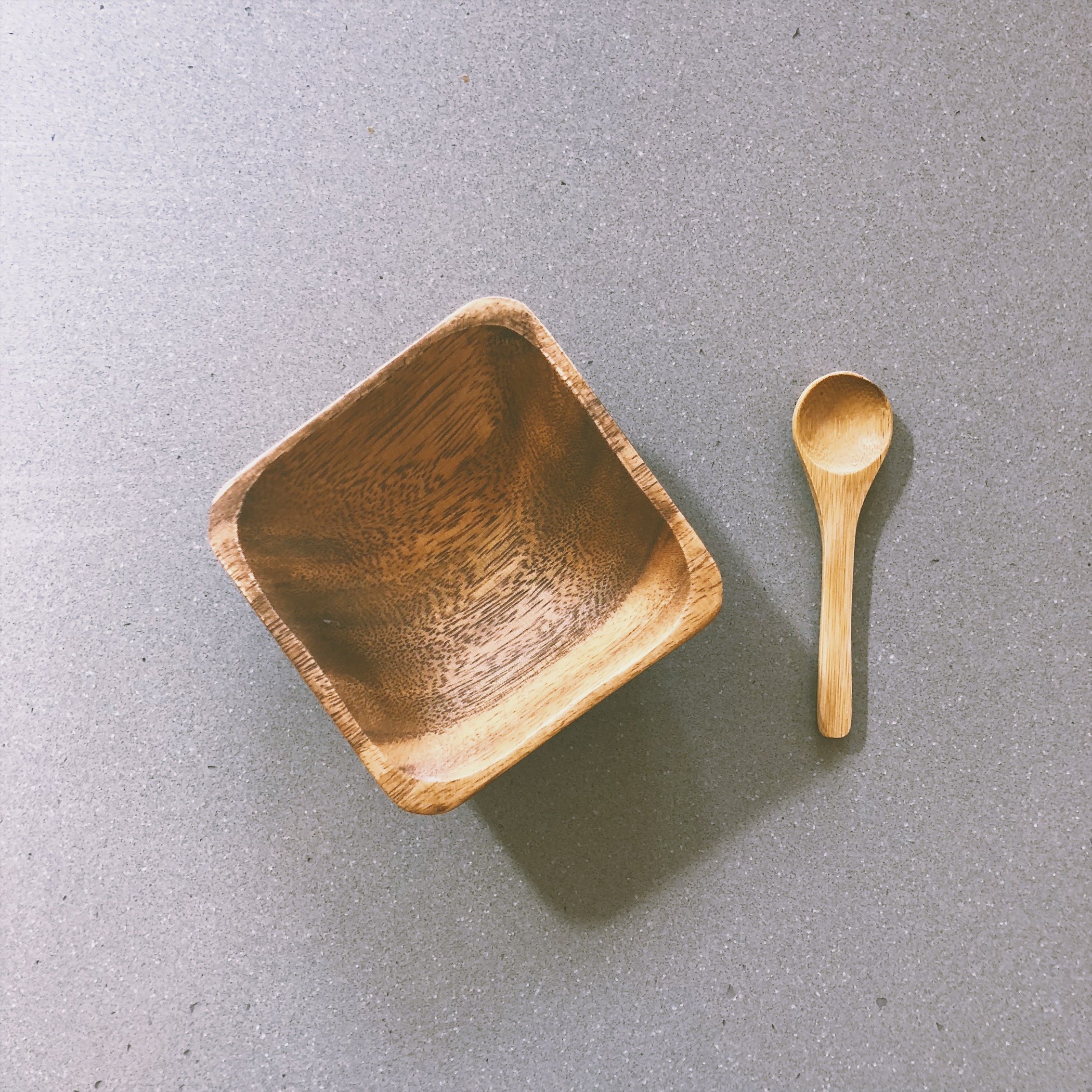 Eco-friendly bamboo spoon and acacia bowl for mixing skincare products, accompanied by a muslin travel pouch.