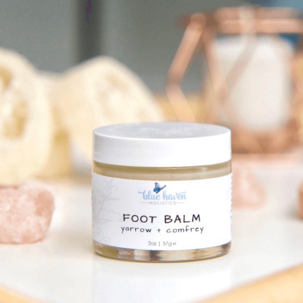 A jar of Yarrow + Comfrey Foot Balm, showcasing its creamy texture and natural ingredients, ideal for treating dry, cracked feet.