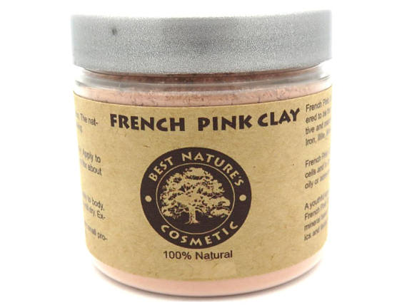 A bowl of French Pink Clay powder with a wooden spoon, showcasing its fine texture and soft pink hue, ideal for skincare applications.