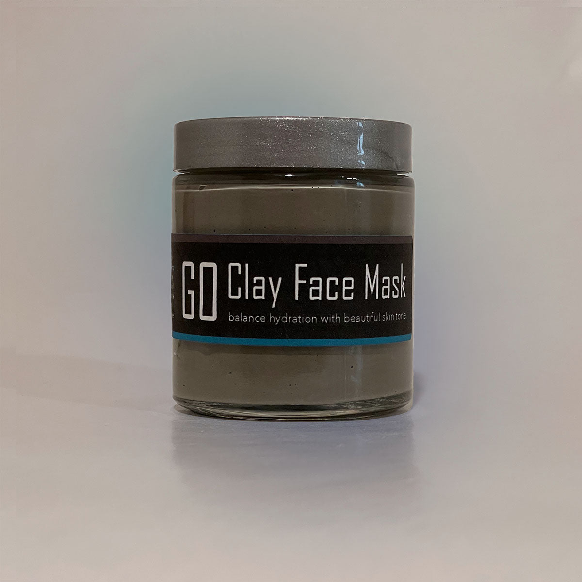 GO Clay Mask in a jar, showcasing its smooth grey texture and natural ingredients, perfect for rejuvenating and soothing the skin.