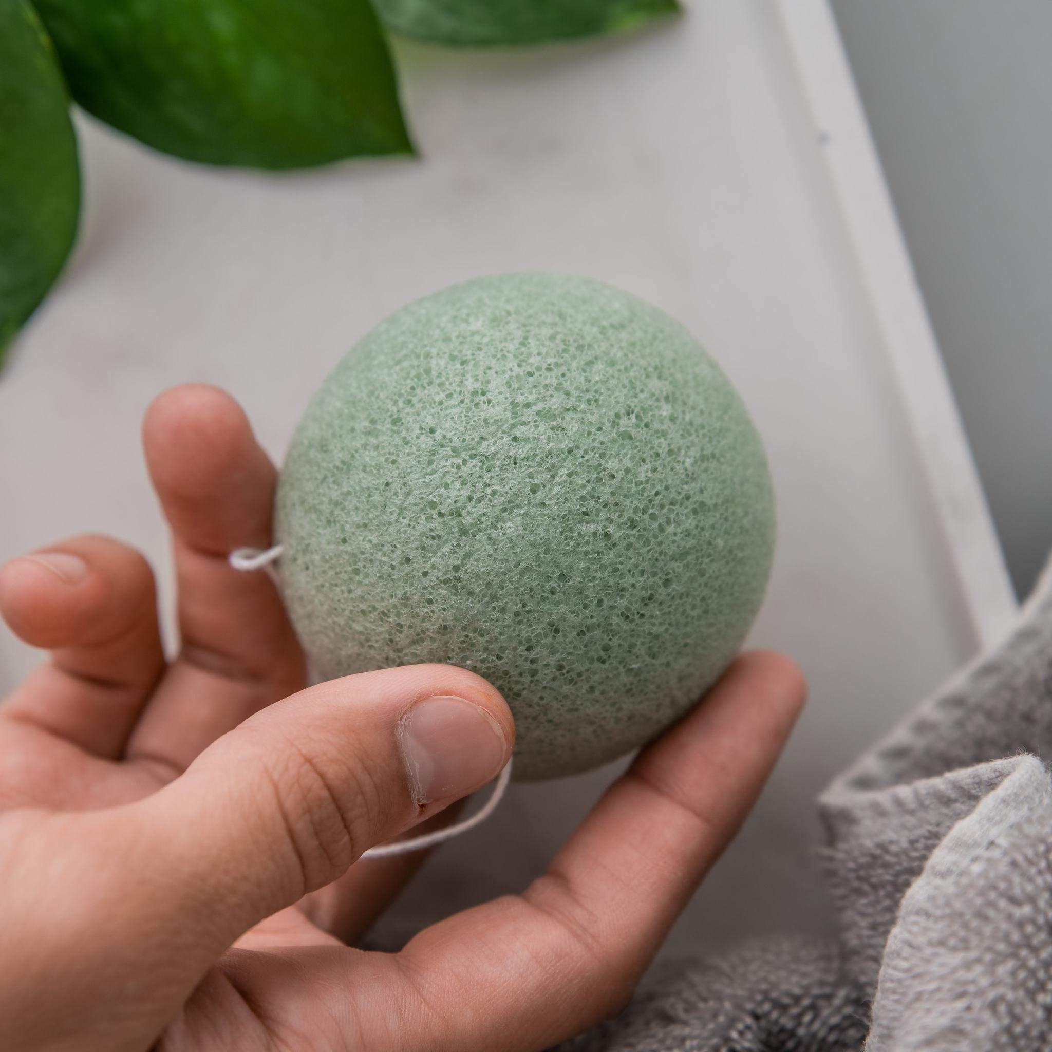 A collection of five biodegradable Konjac sponges in various colors, each representing different skin benefits, displayed on a natural wooden surface.