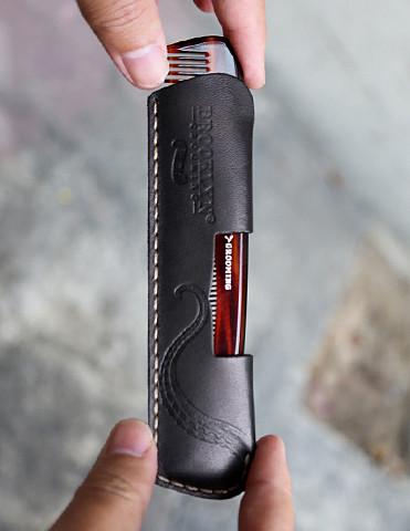 A luxurious leather comb sleeve with a pocket comb, featuring black leather and gold stitching, handcrafted in the USA.