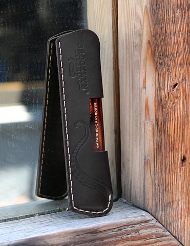 A luxurious leather comb sleeve with a pocket comb, featuring black leather and gold stitching, handcrafted in the USA.