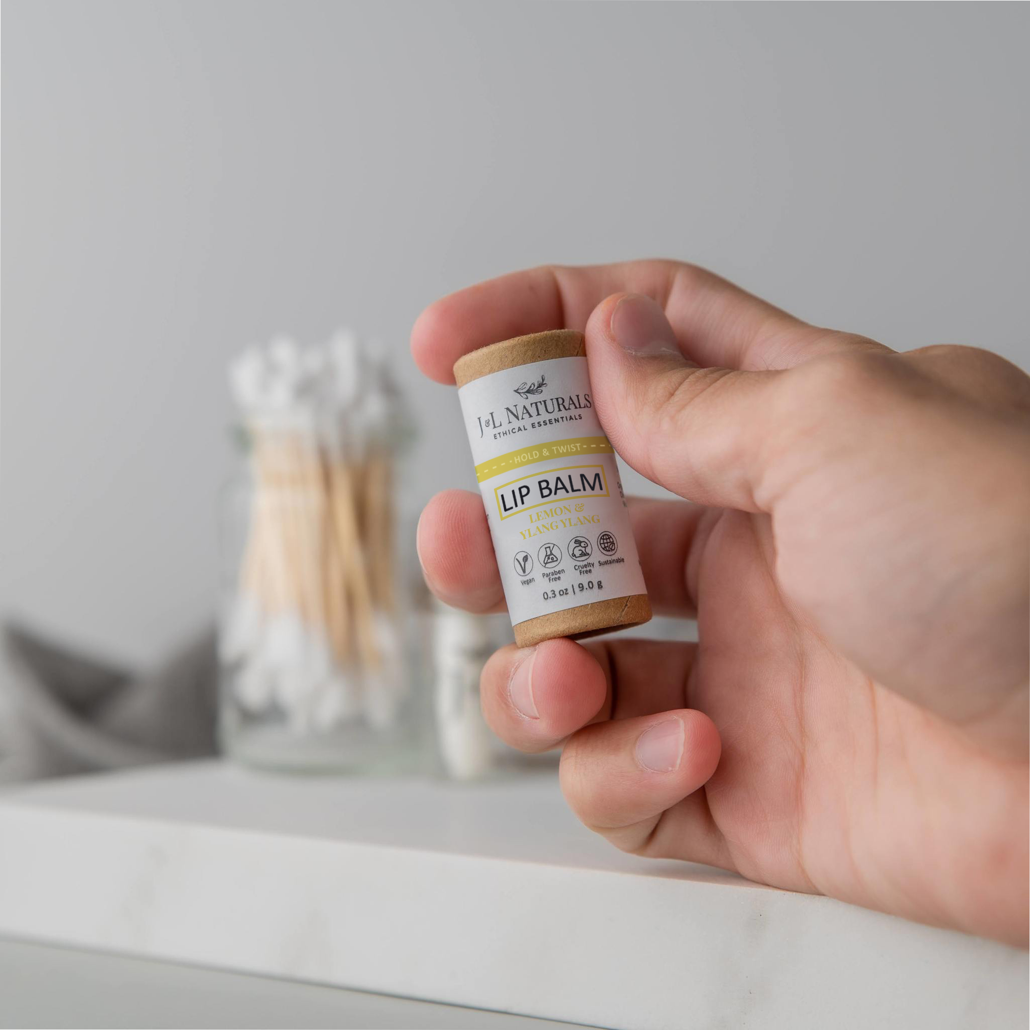 A collection of six lip balms in various flavors including unscented, peppermint, lemongrass, strawberry, bergamot, and lemon, displayed on a wooden surface.