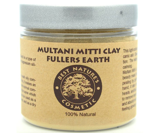 A bowl of light-colored Multani Mitti clay with a smooth texture, surrounded by natural ingredients like rose petals and a small wooden spatula, showcasing its skincare benefits.